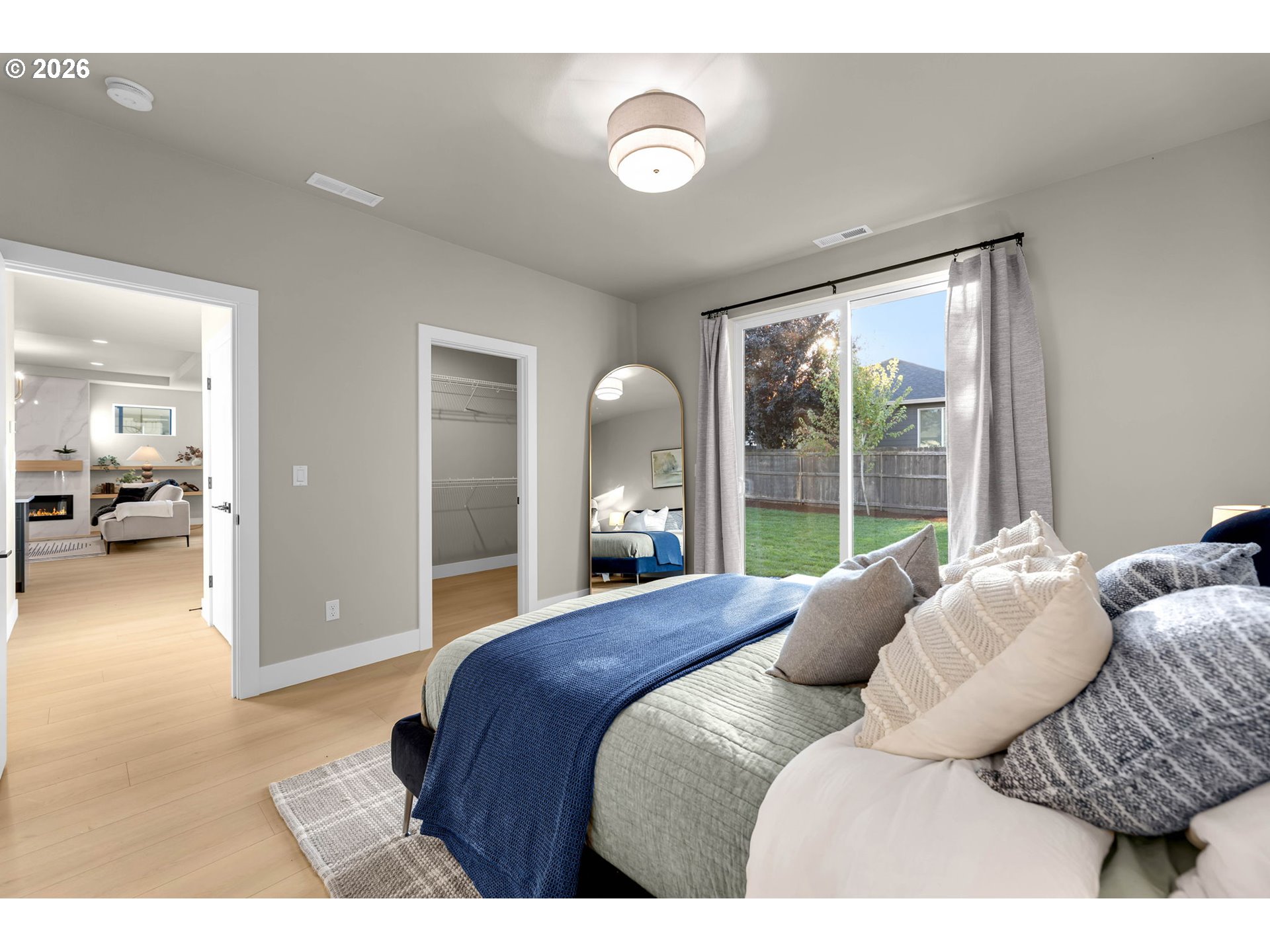 Staged bedroom with blue bedding, an open closet, and a sliding glass door to the fenced backyard.