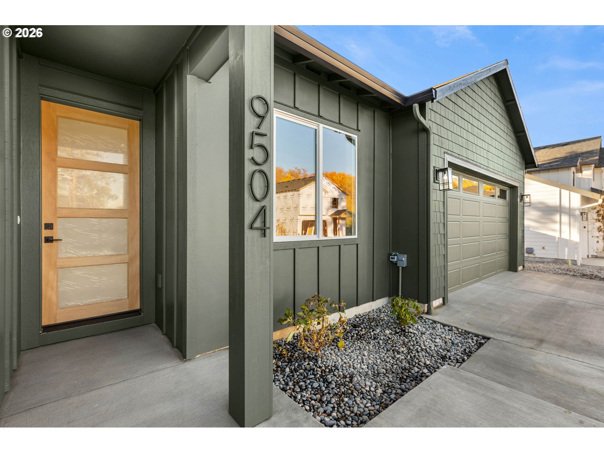 Dark green home entrance with a wood-and-glass door, address number 9504, and attached garage.