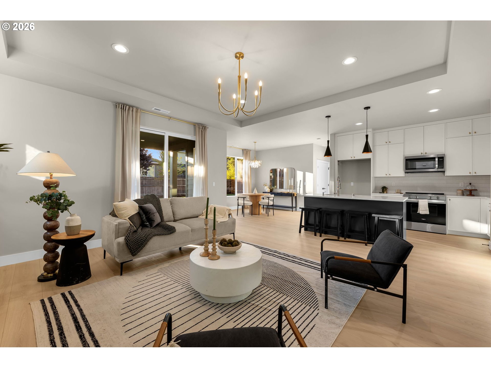 Open-plan living room and kitchen with a striped rug, black island, and sliding glass doors.