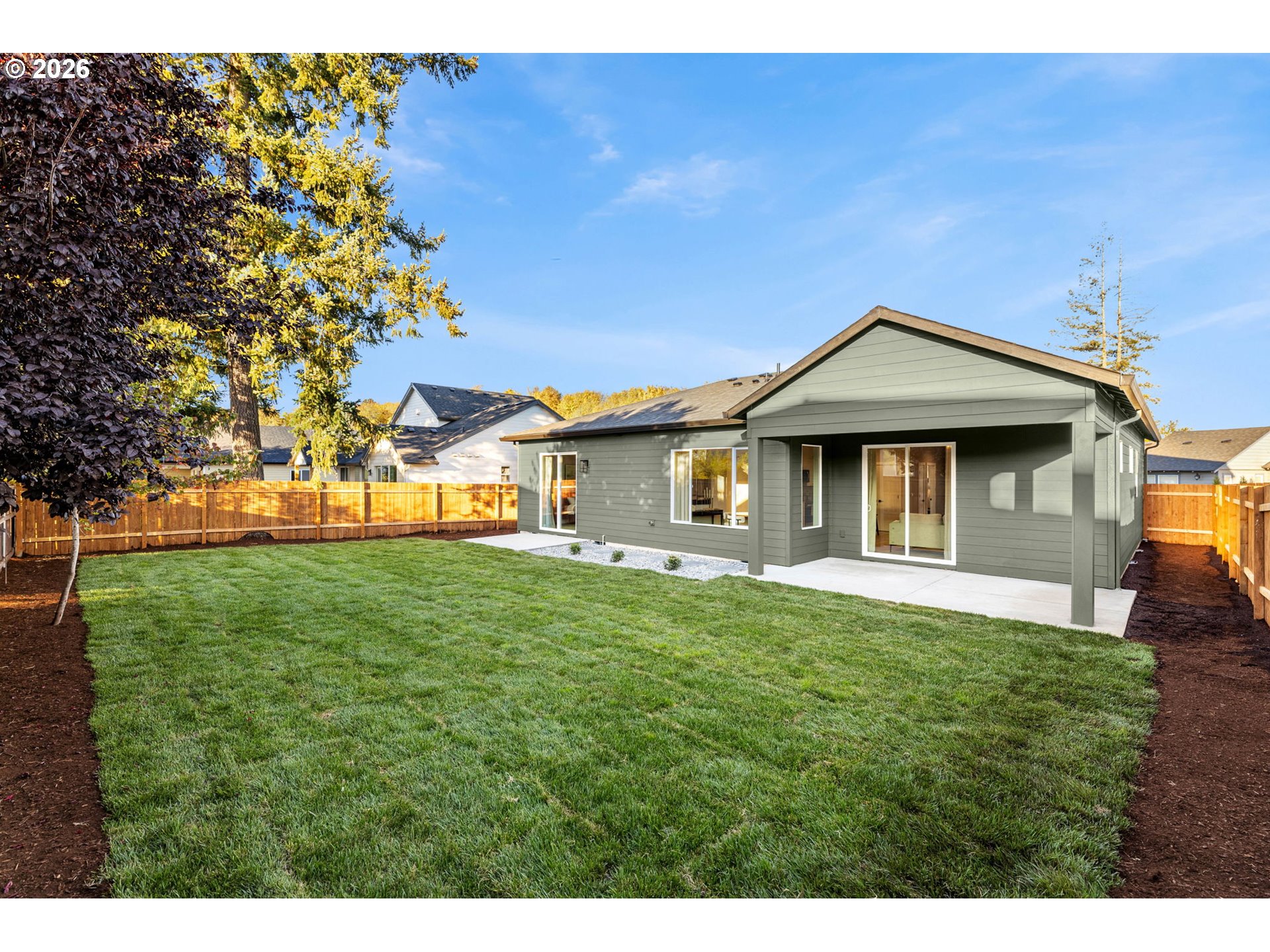 Gray-sided home with covered patio and fenced backyard lawn.