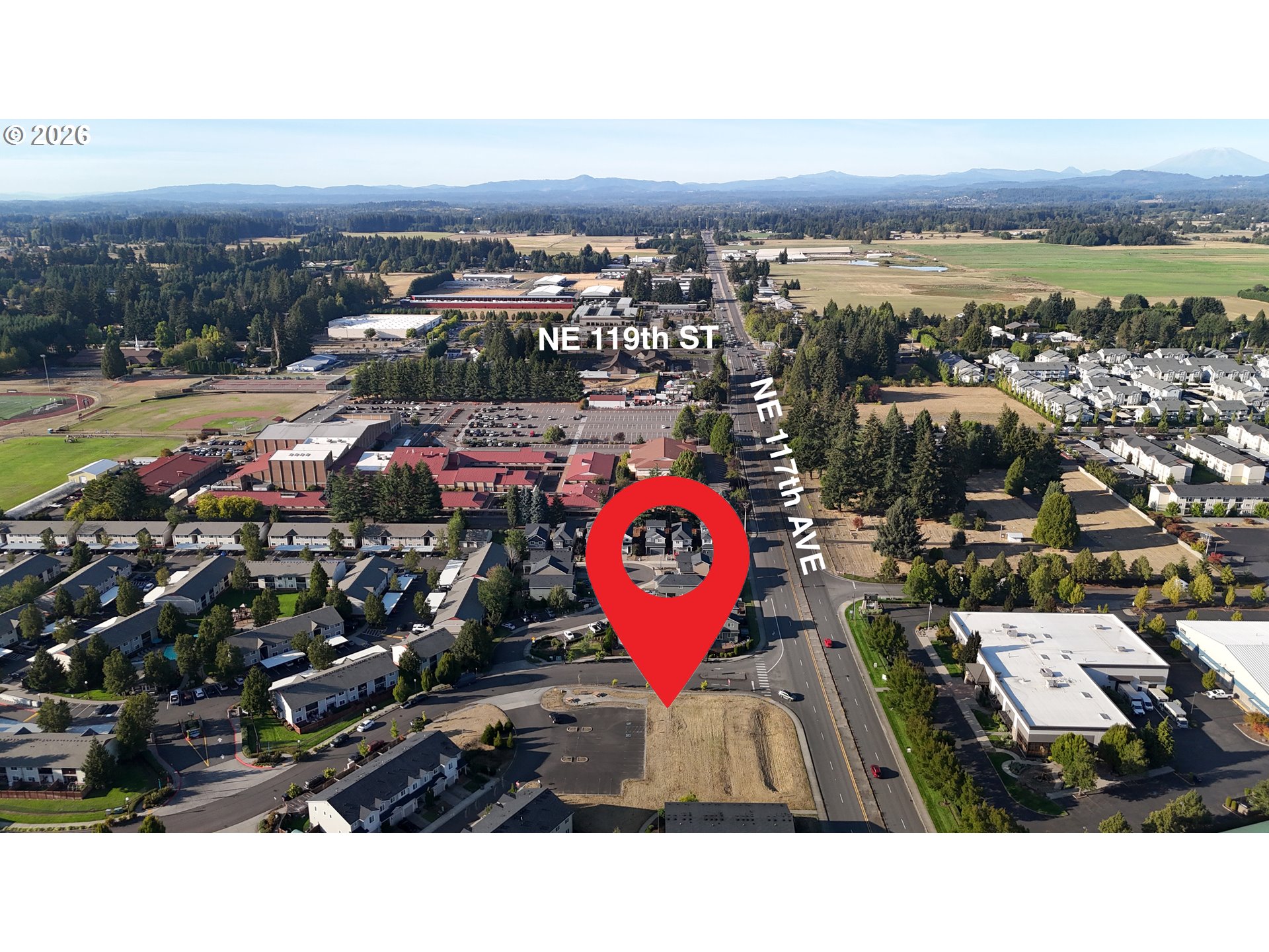 Aerial neighborhood view with the property marked by a red pin and mountains in the distance.
