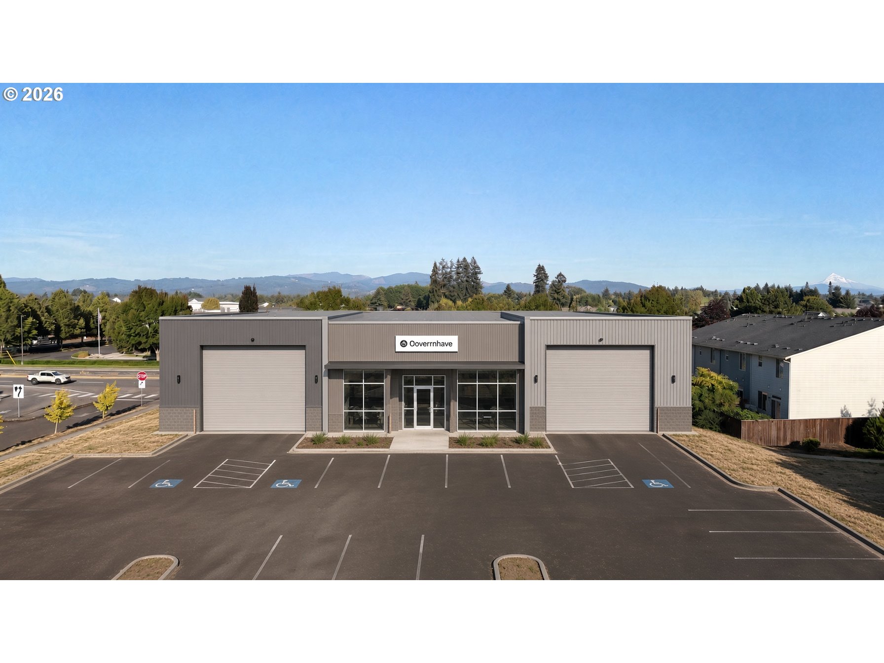 Modern gray commercial building with two roll-up doors, accessible parking, and distant mountain views.