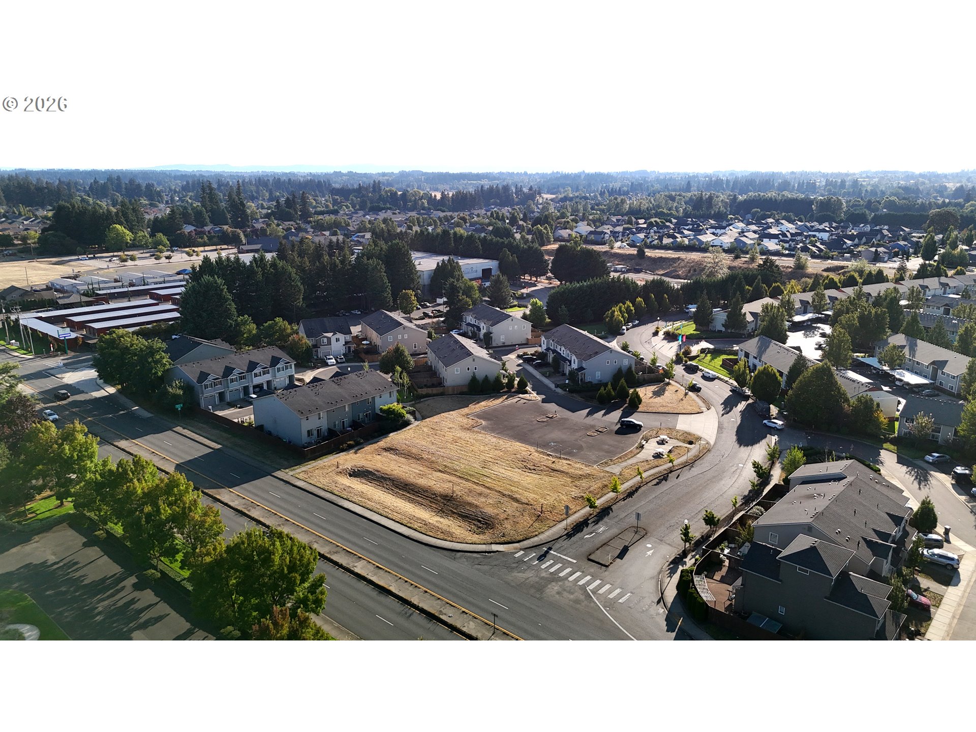 Aerial view of a vacant lot at a residential intersection, surrounded by homes and trees.