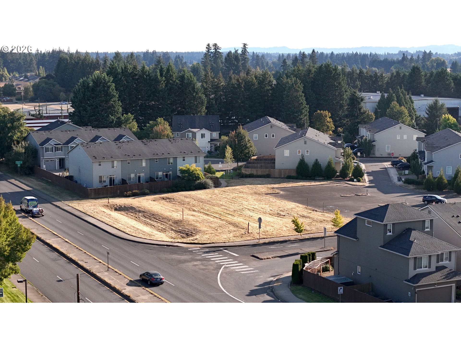Cleared corner lot at a street intersection, surrounded by homes and mature trees.
