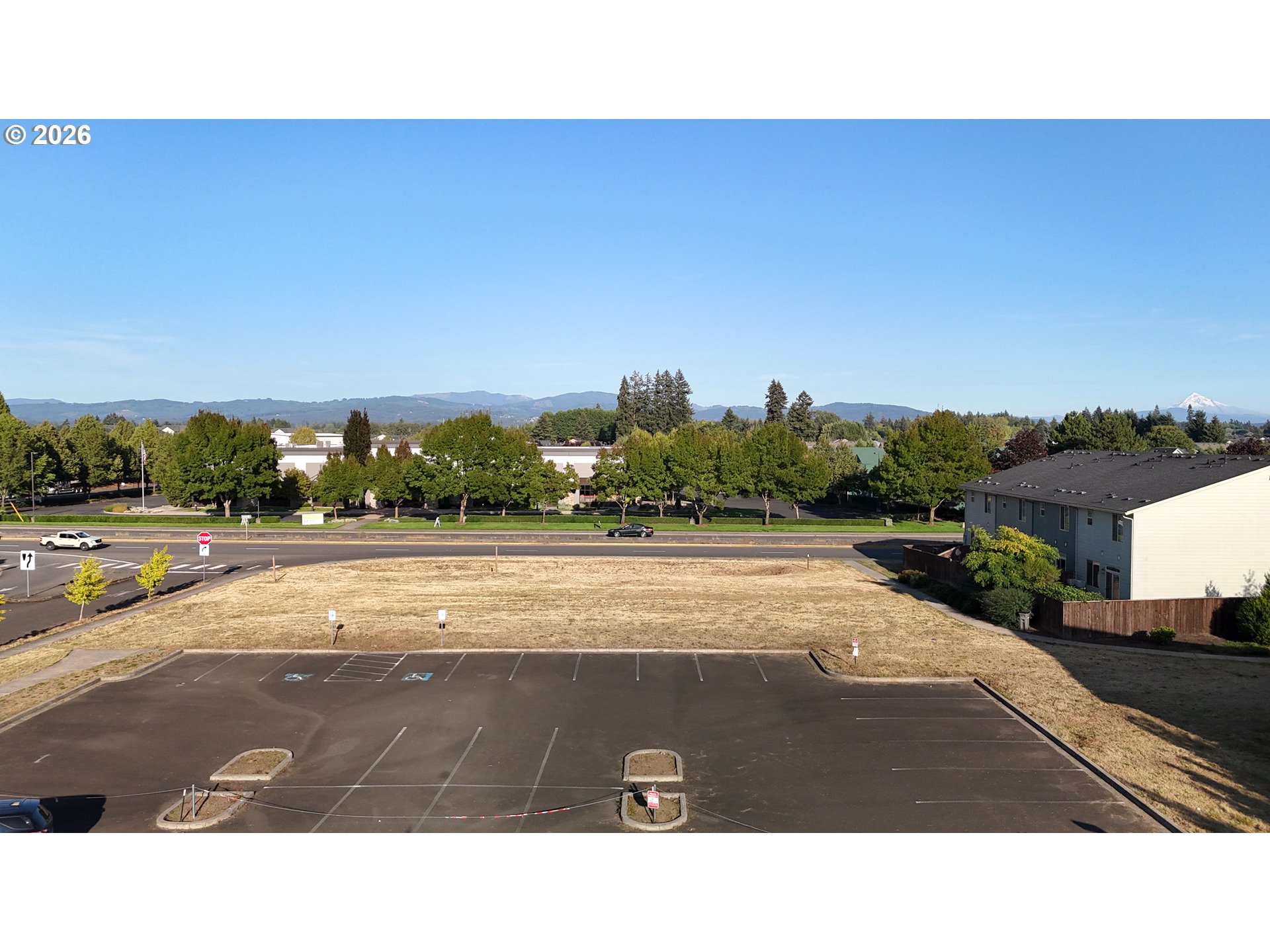 Vacant lot beside a road, with distant mountains and a snow-capped peak.