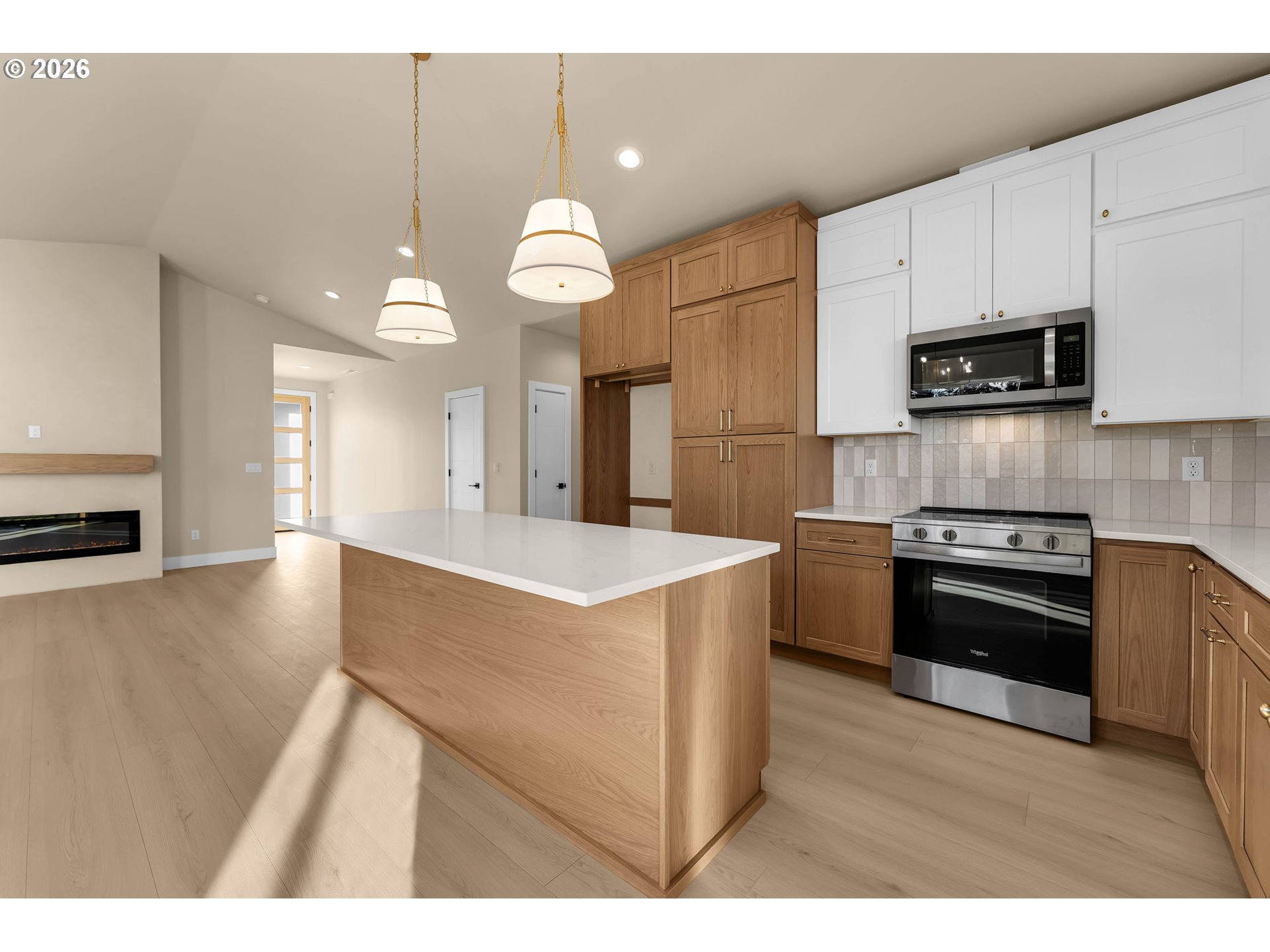 Modern kitchen with a large wood island, mixed cabinetry, stainless steel appliances, and pendant lights.