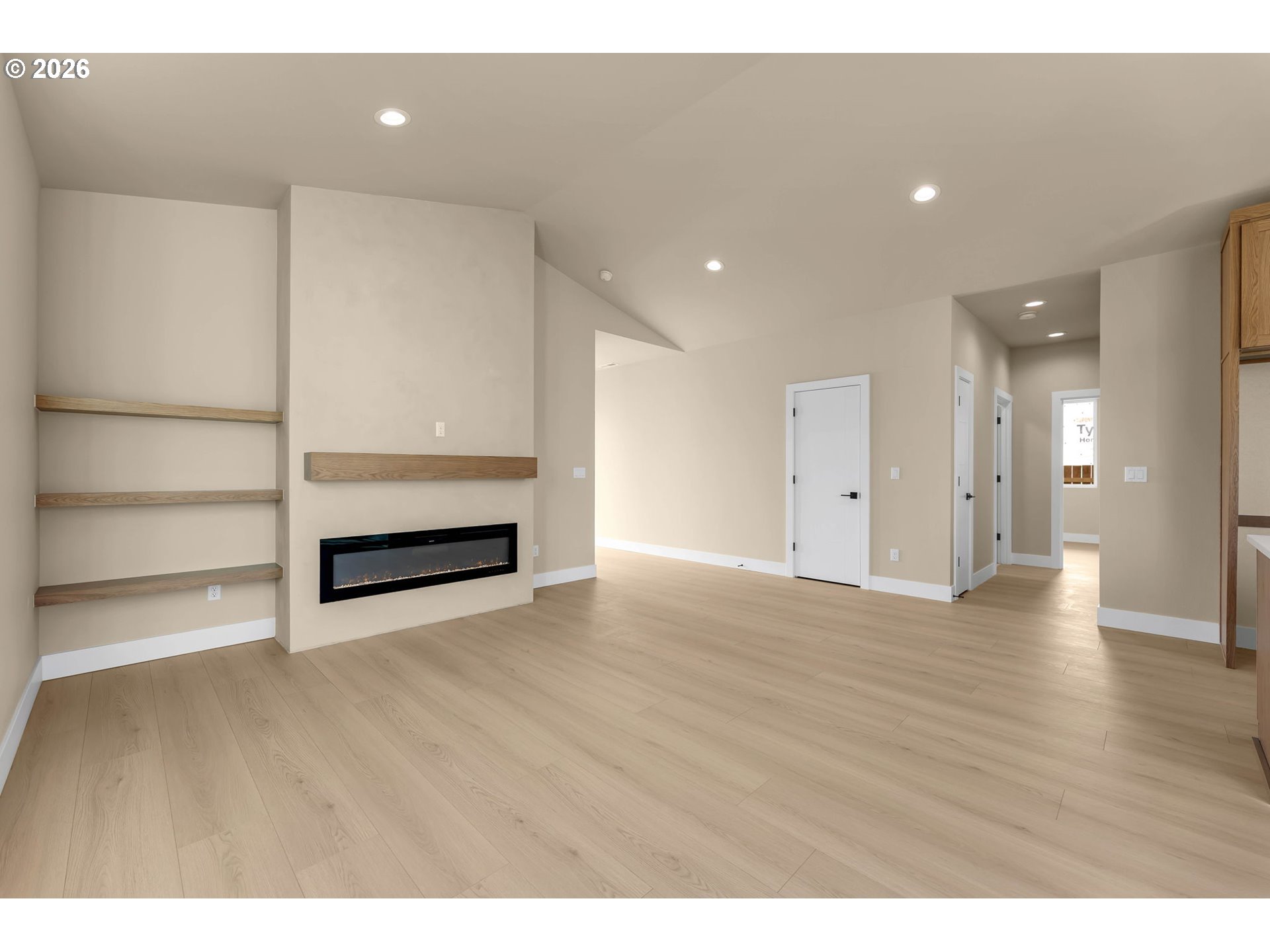 Vacant living room with pale wood floors, built-in shelves, and a linear fireplace.