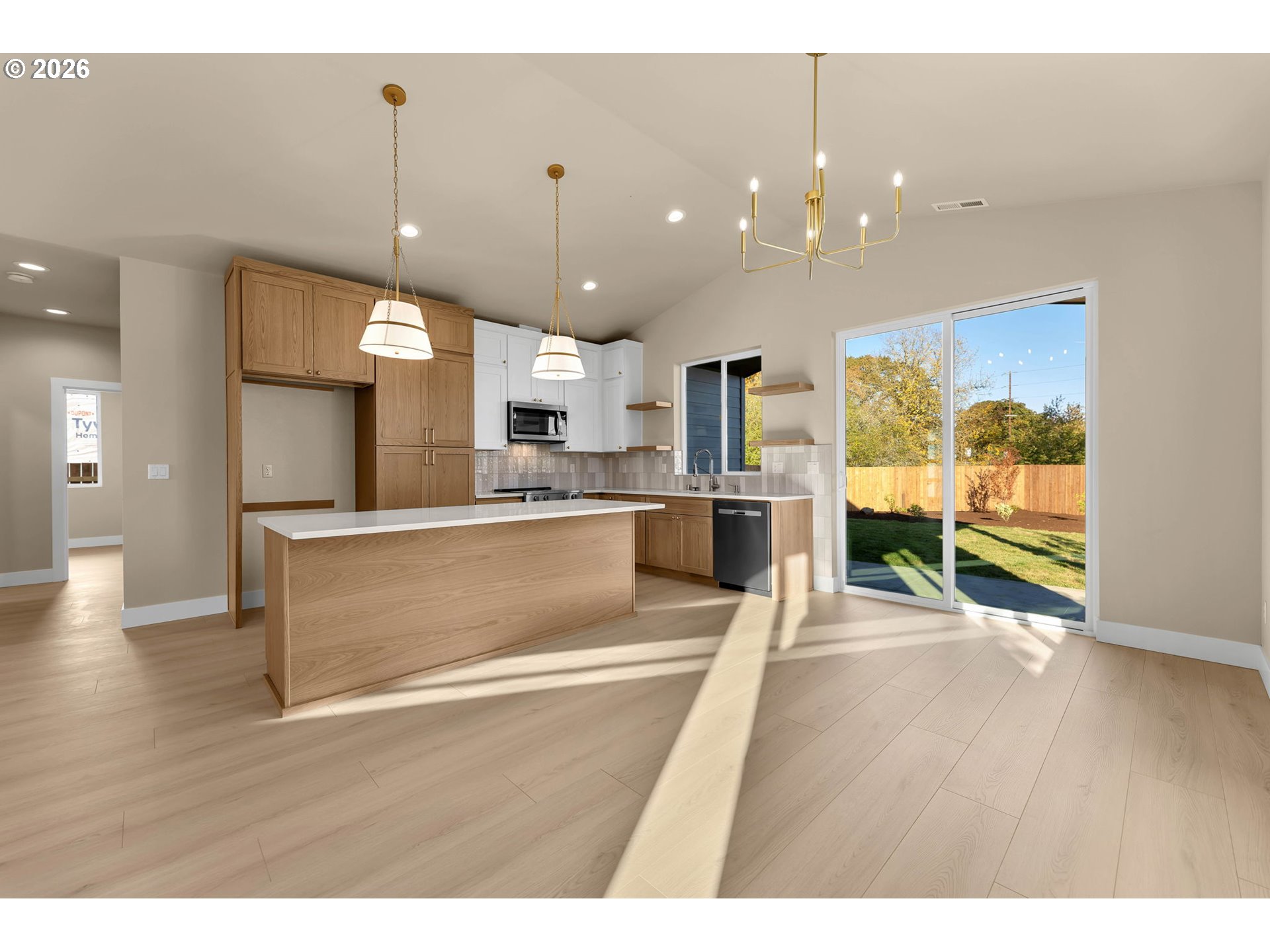 Kitchen with a large wood island and sliding glass doors opening to a sunny fenced backyard.