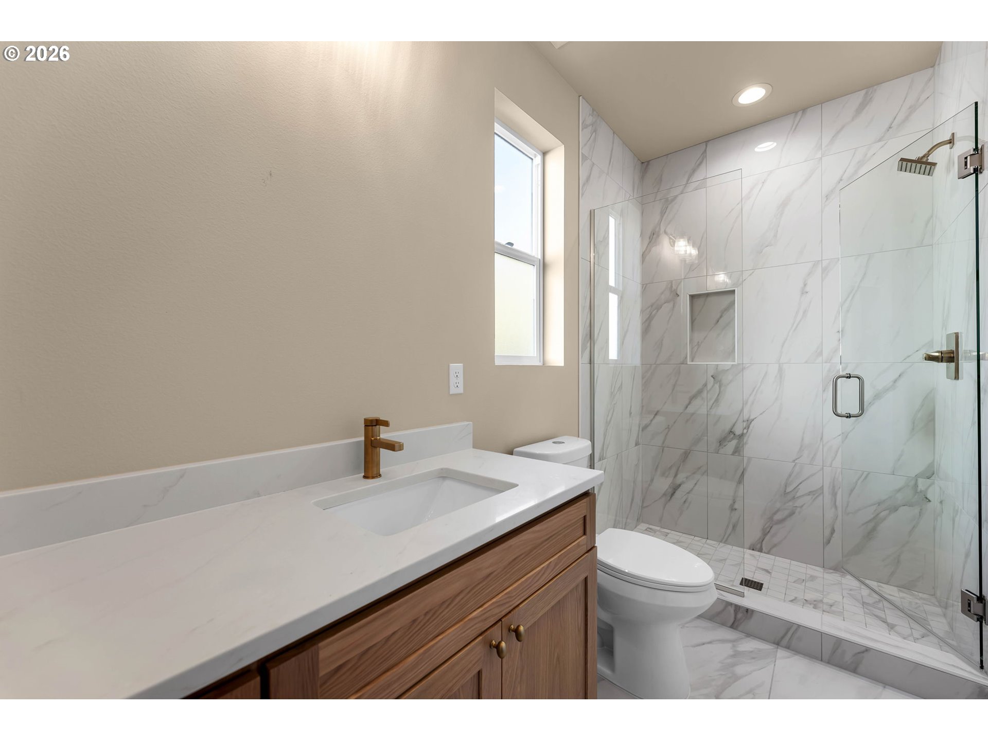 Modern bathroom with a wood vanity and marble-look tiled walk-in shower.