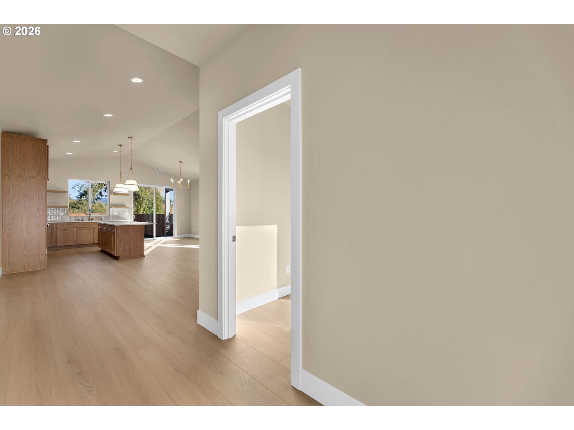 Open-plan kitchen with warm wood cabinetry, a central island, and light wood floors.