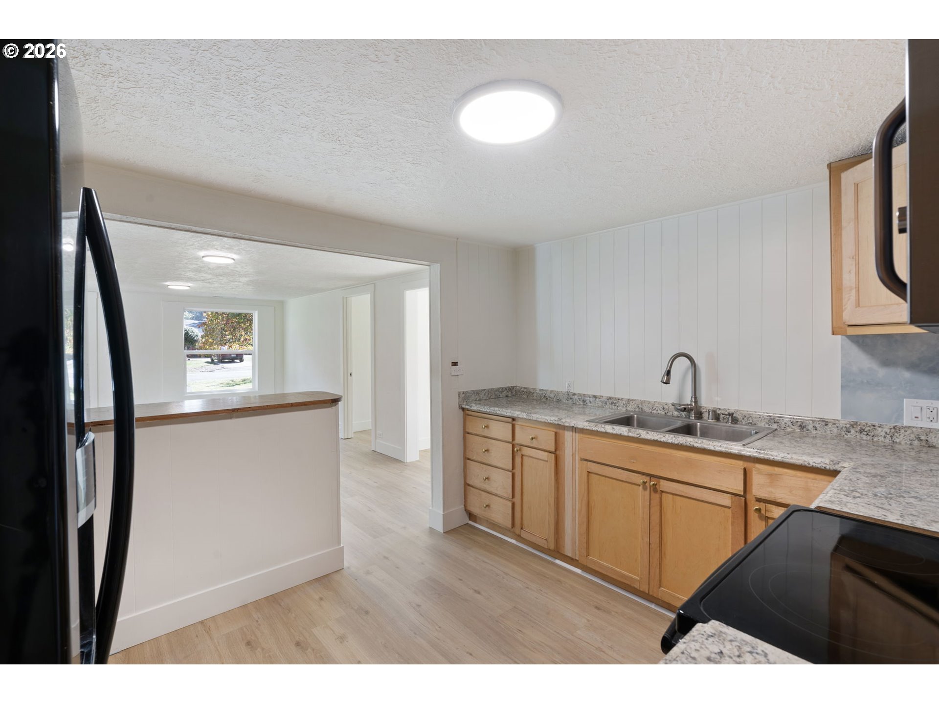 Unfurnished kitchen with light wood cabinets, granite countertops, and a double-basin sink.