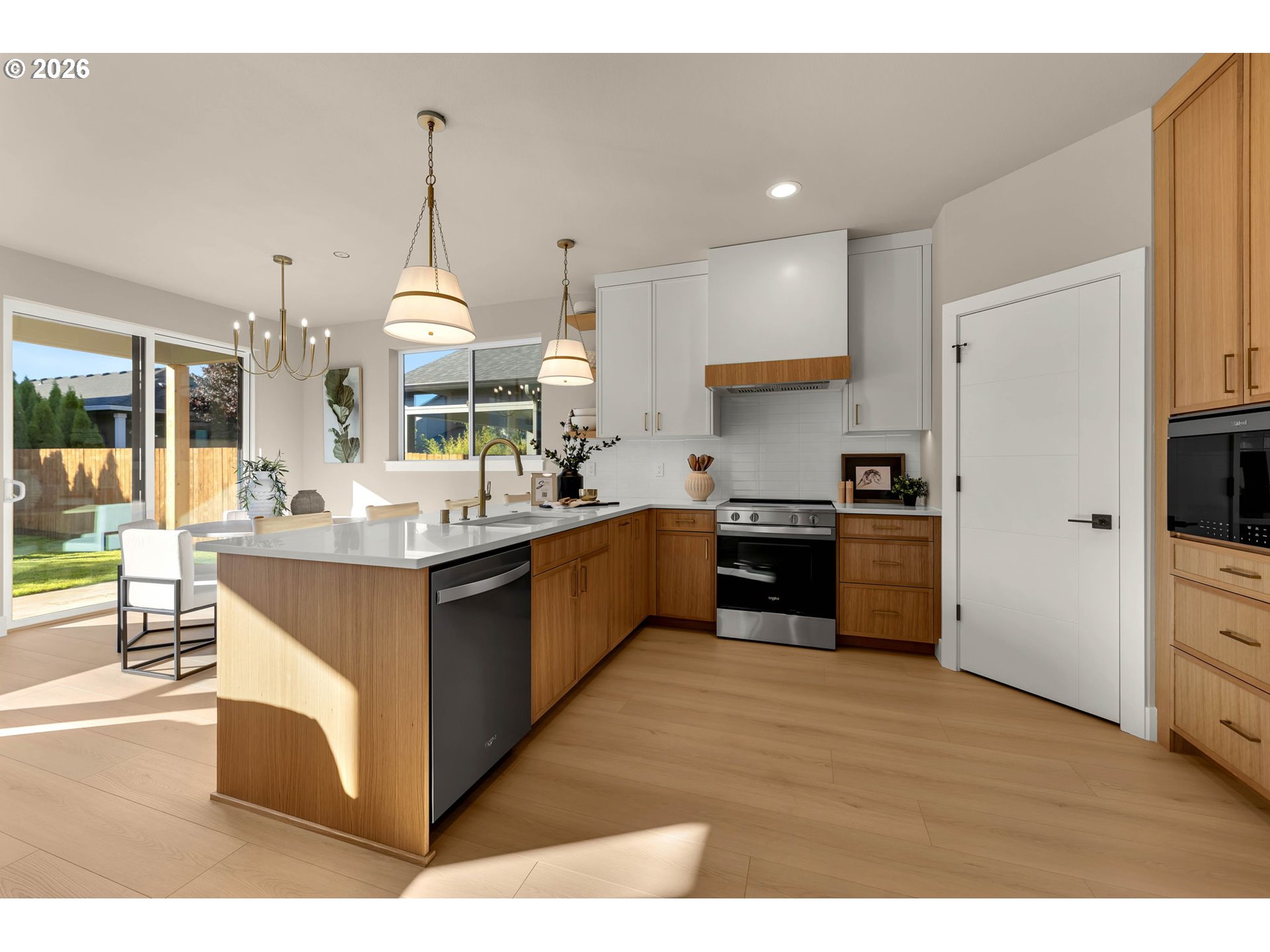 Modern kitchen with a wood-front island, white counters, pendant lights, and sliding doors to the backyard.