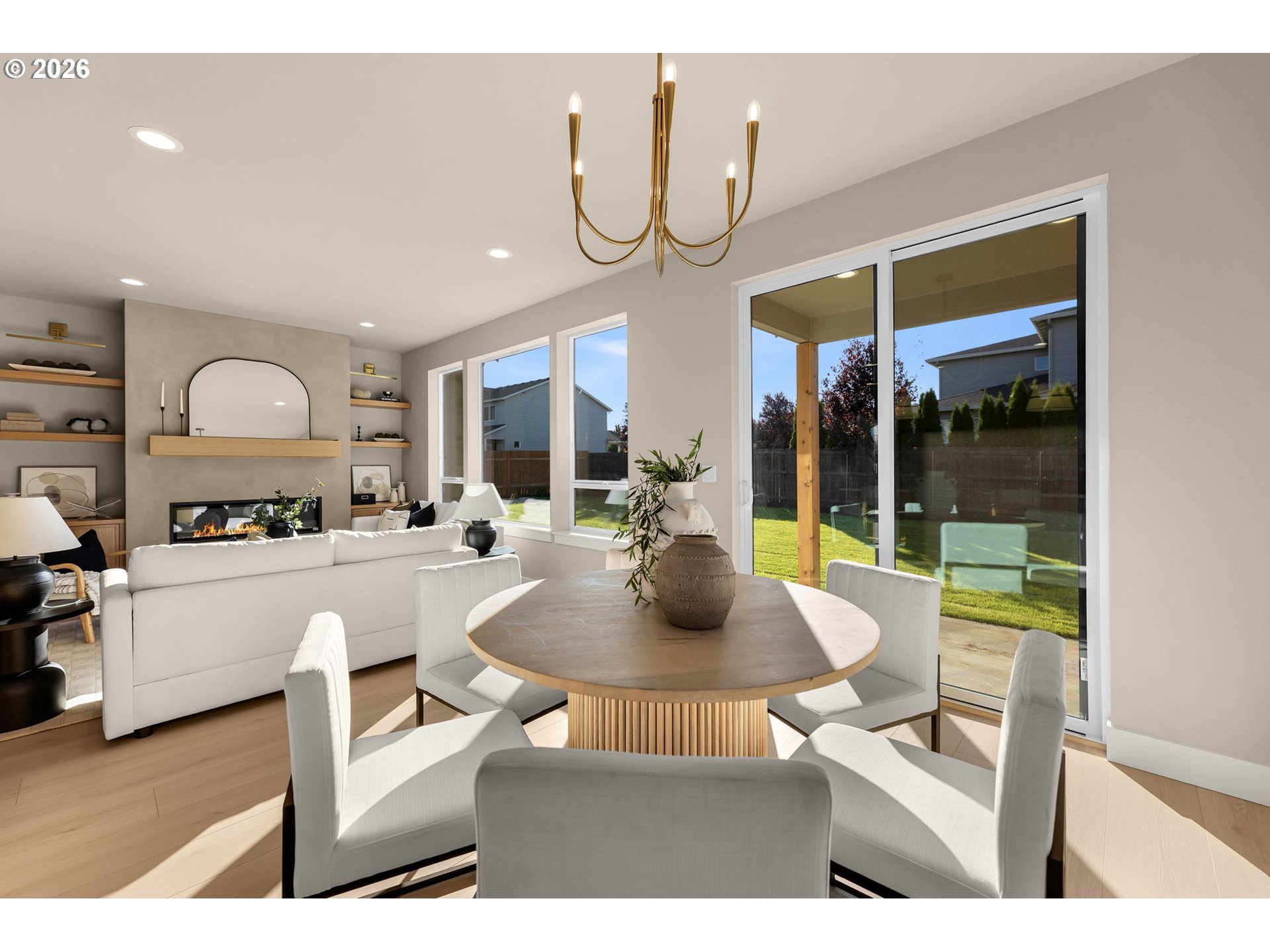 Open-plan dining and living room with a fireplace and large sliding glass doors to the backyard.