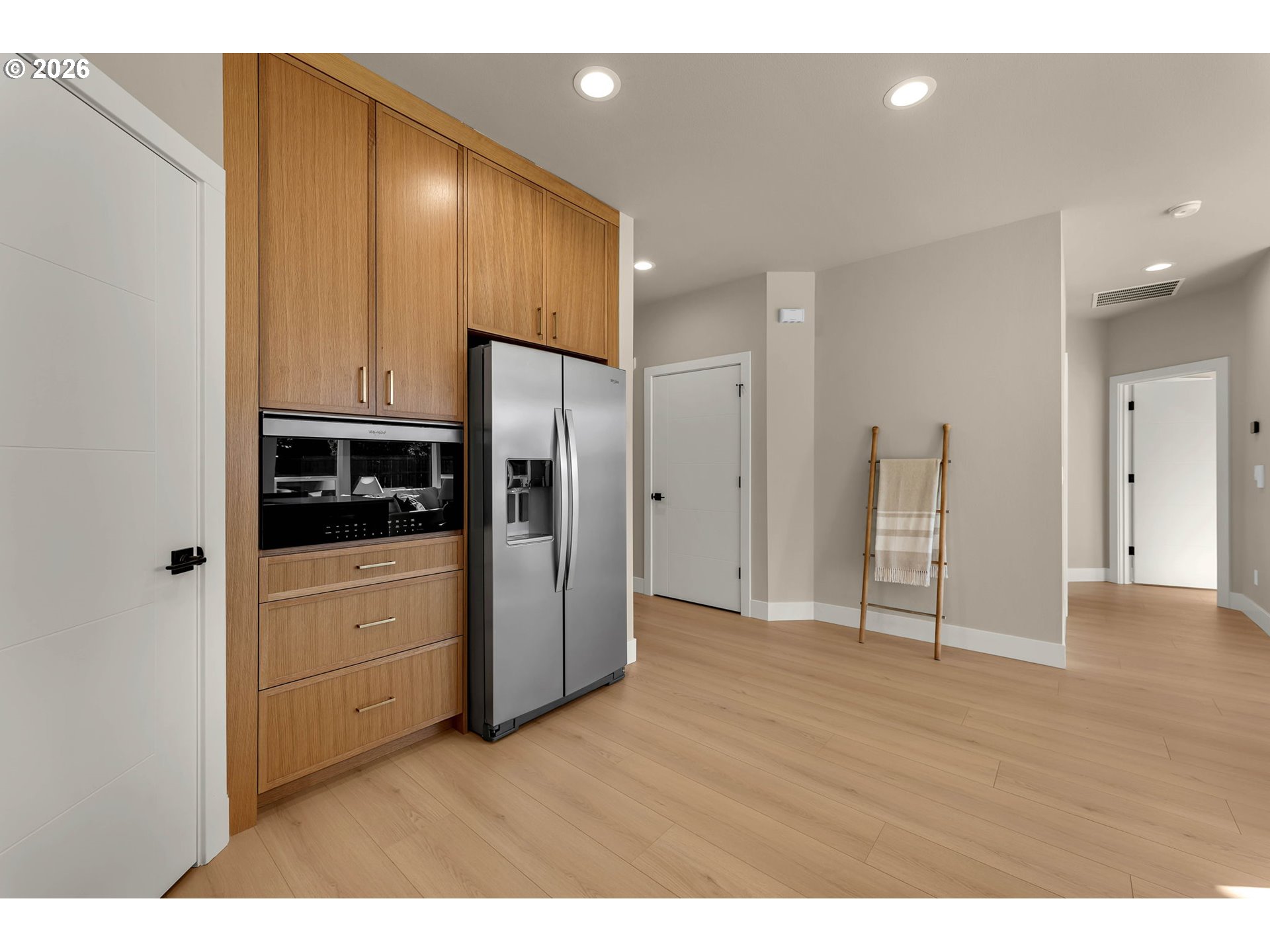 Kitchen with tall wood cabinetry, built-in double ovens, and a stainless steel refrigerator.