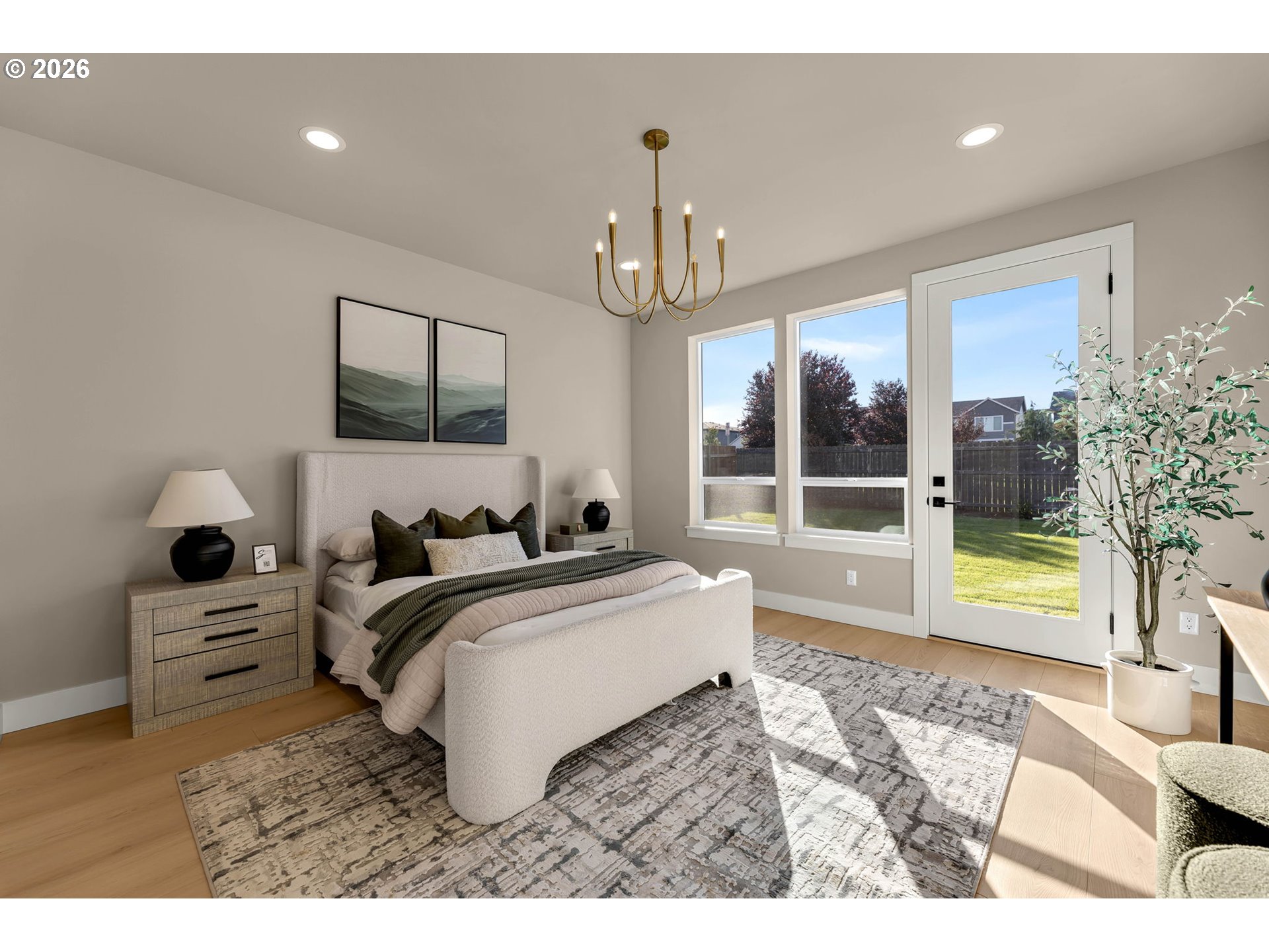 Staged bedroom with a cream bed, patterned rug, and glass door overlooking a fenced backyard.