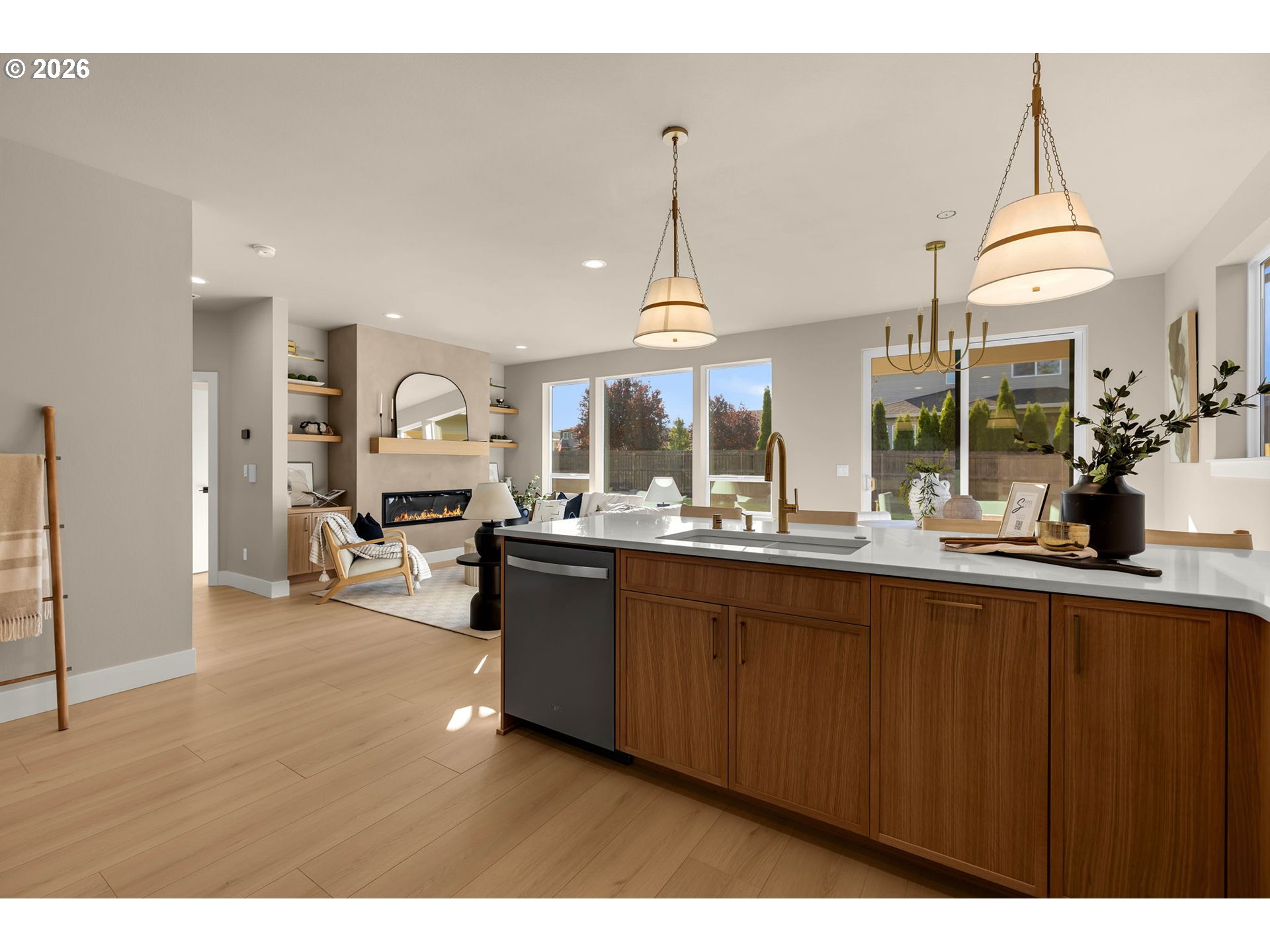 Open-plan kitchen with a walnut island and white counters, adjoining a living area with a fireplace.