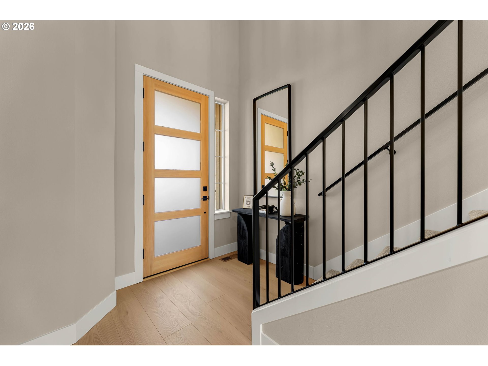 Entry foyer with a frosted-panel wood front door and black-railed staircase.