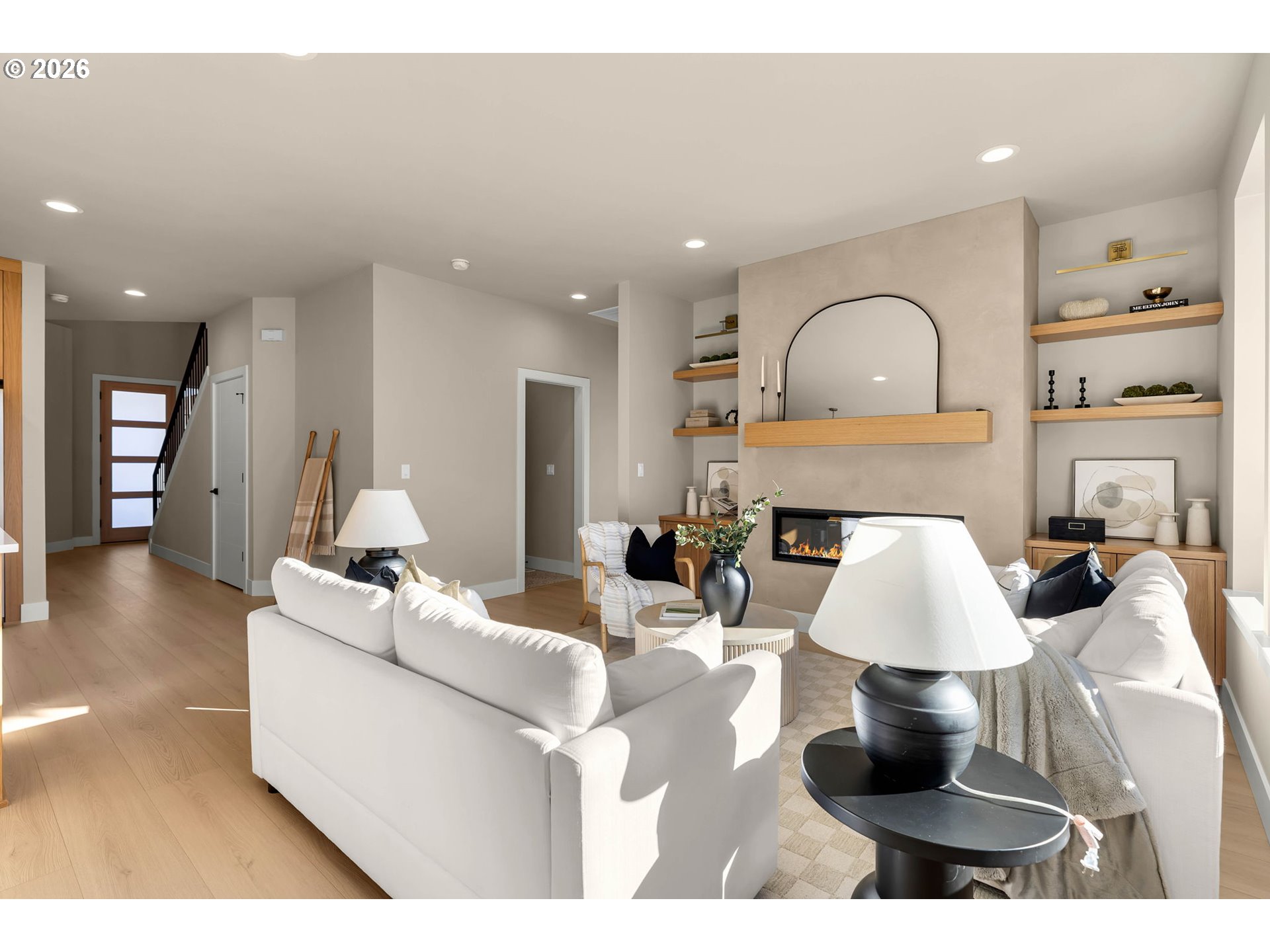 Living room with white sofas, a modern fireplace, and built-in display shelves.