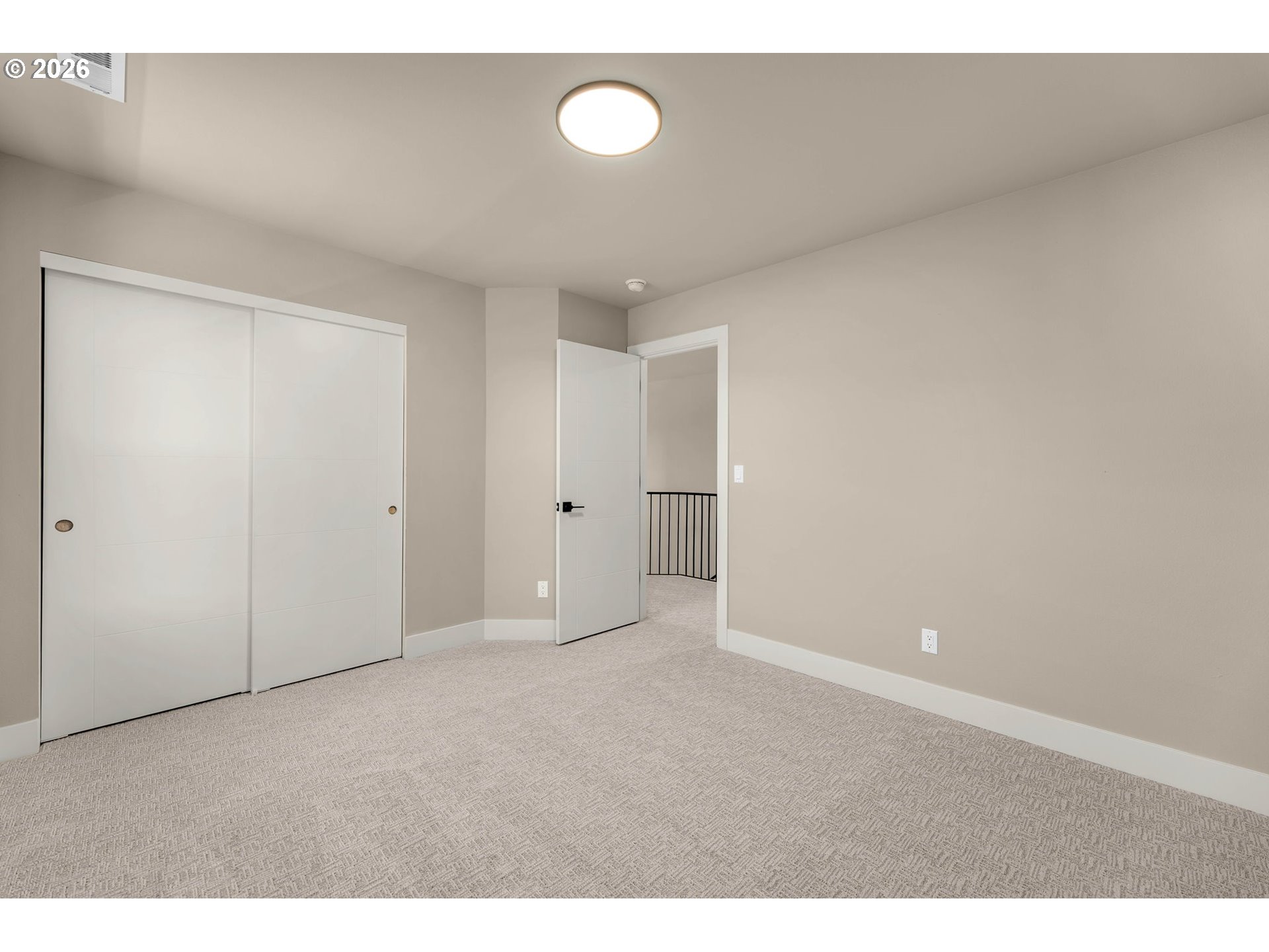 Empty carpeted bedroom with sliding closet doors and an open doorway to a landing.