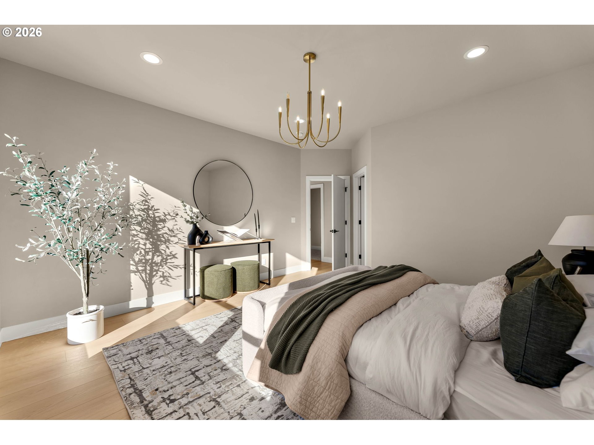 Staged bedroom with a round mirror, brass chandelier, and sunlit wood floors