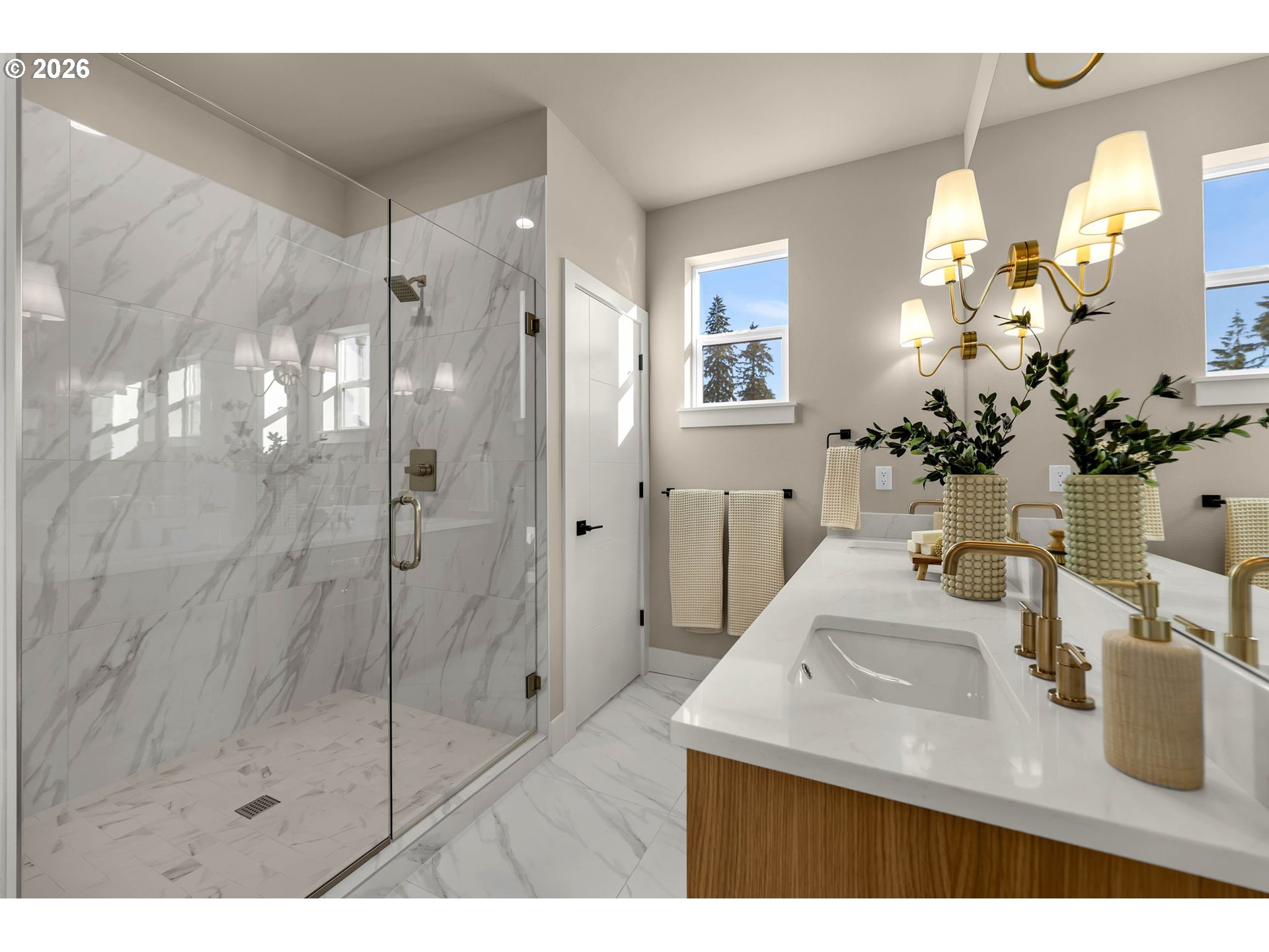 Bathroom with a marble-tiled glass shower and wood-front vanity with gold faucets.