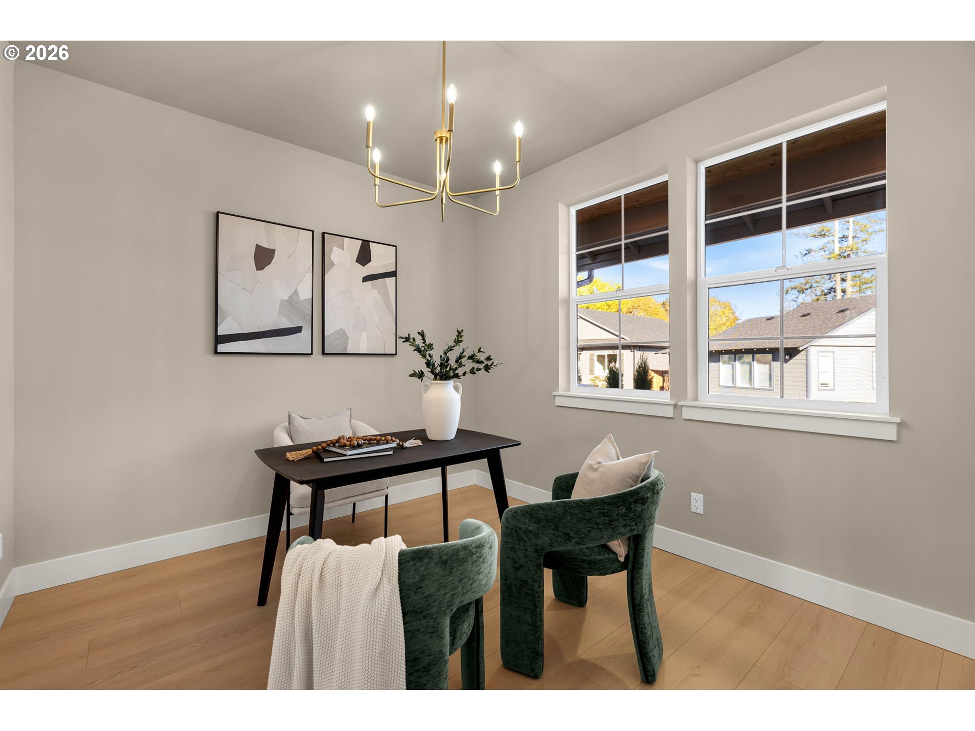 Dining area with a black table, green upholstered chairs, and two large windows.