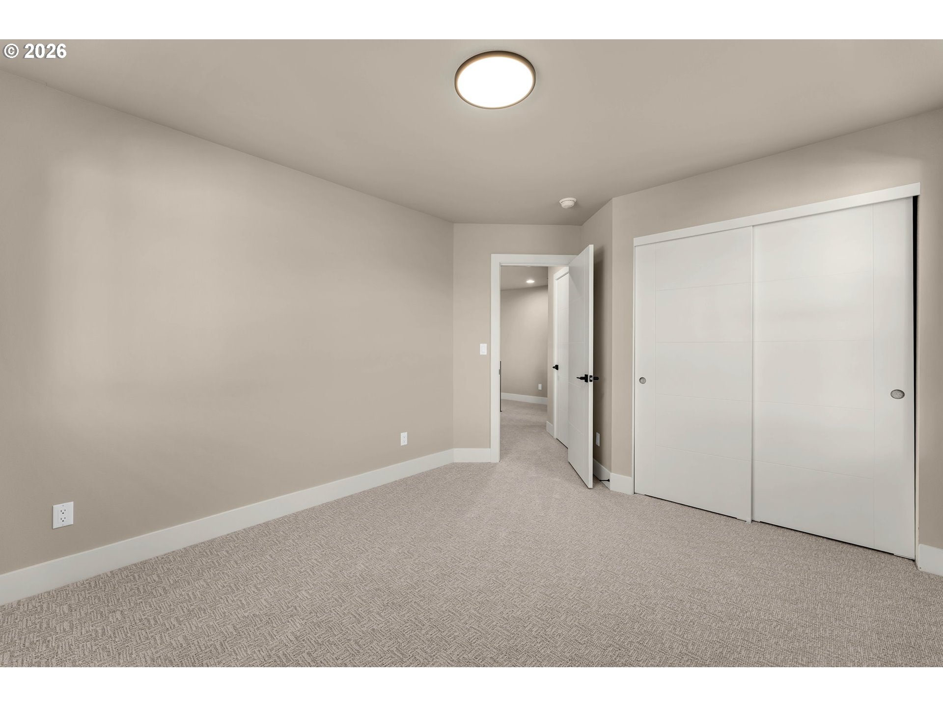 Empty bedroom with patterned carpet and a large white sliding-door closet.