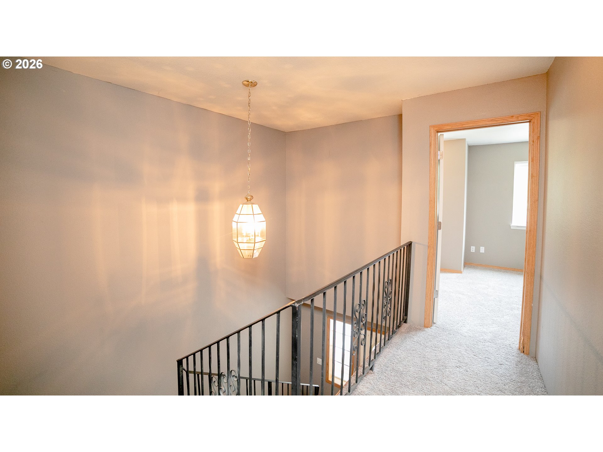 Upstairs landing with a black metal stair railing and illuminated pendant light