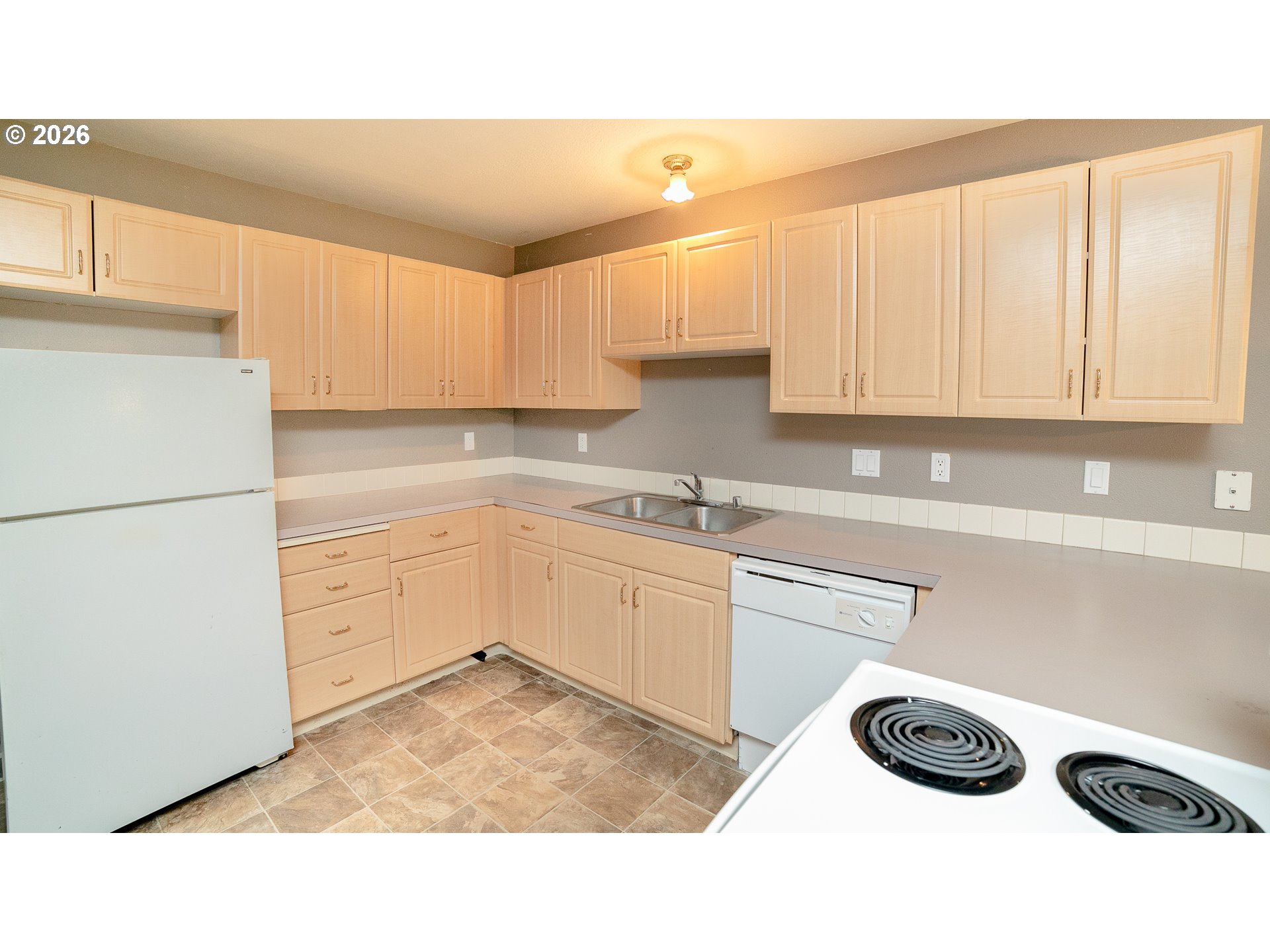 Kitchen with light wood cabinets, a double-basin sink, and white appliances.
