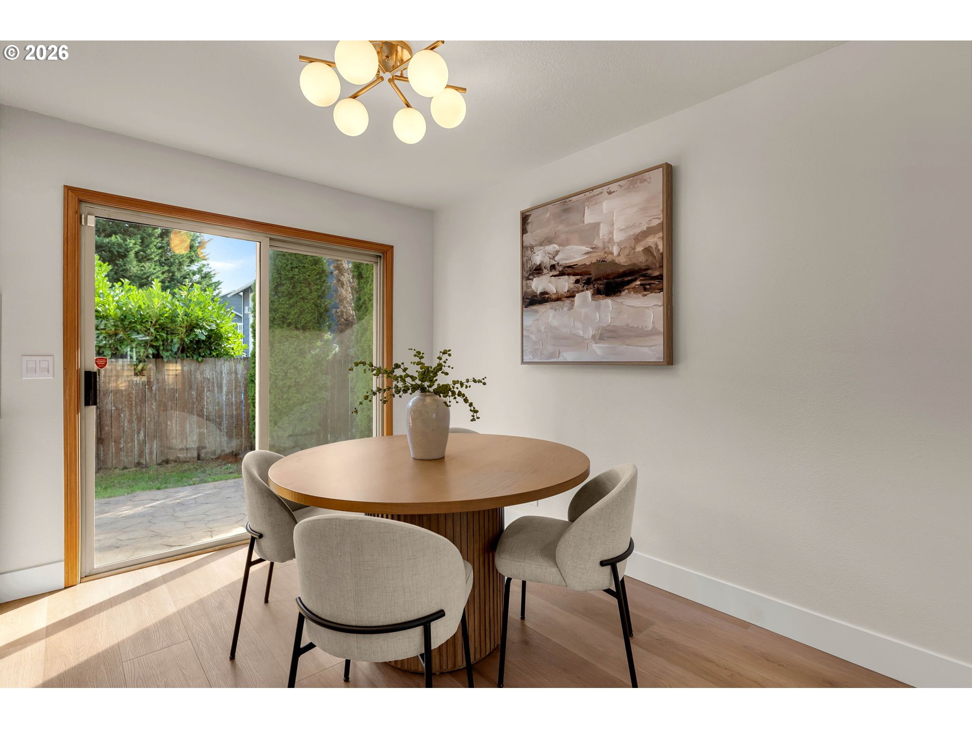 Dining room with a round wood table and sliding glass doors opening onto a fenced patio.