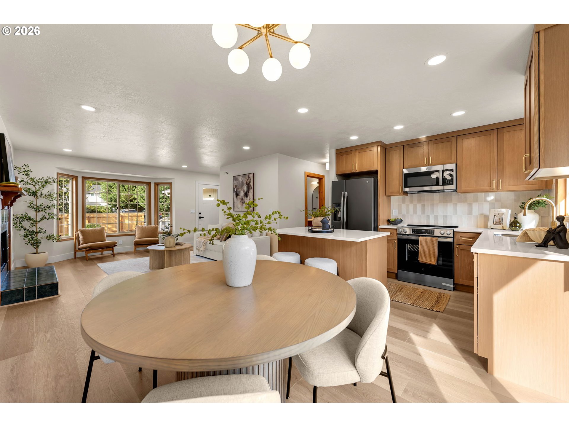 Open-plan kitchen and dining area with wood cabinetry, stainless appliances, and a large round dining table.