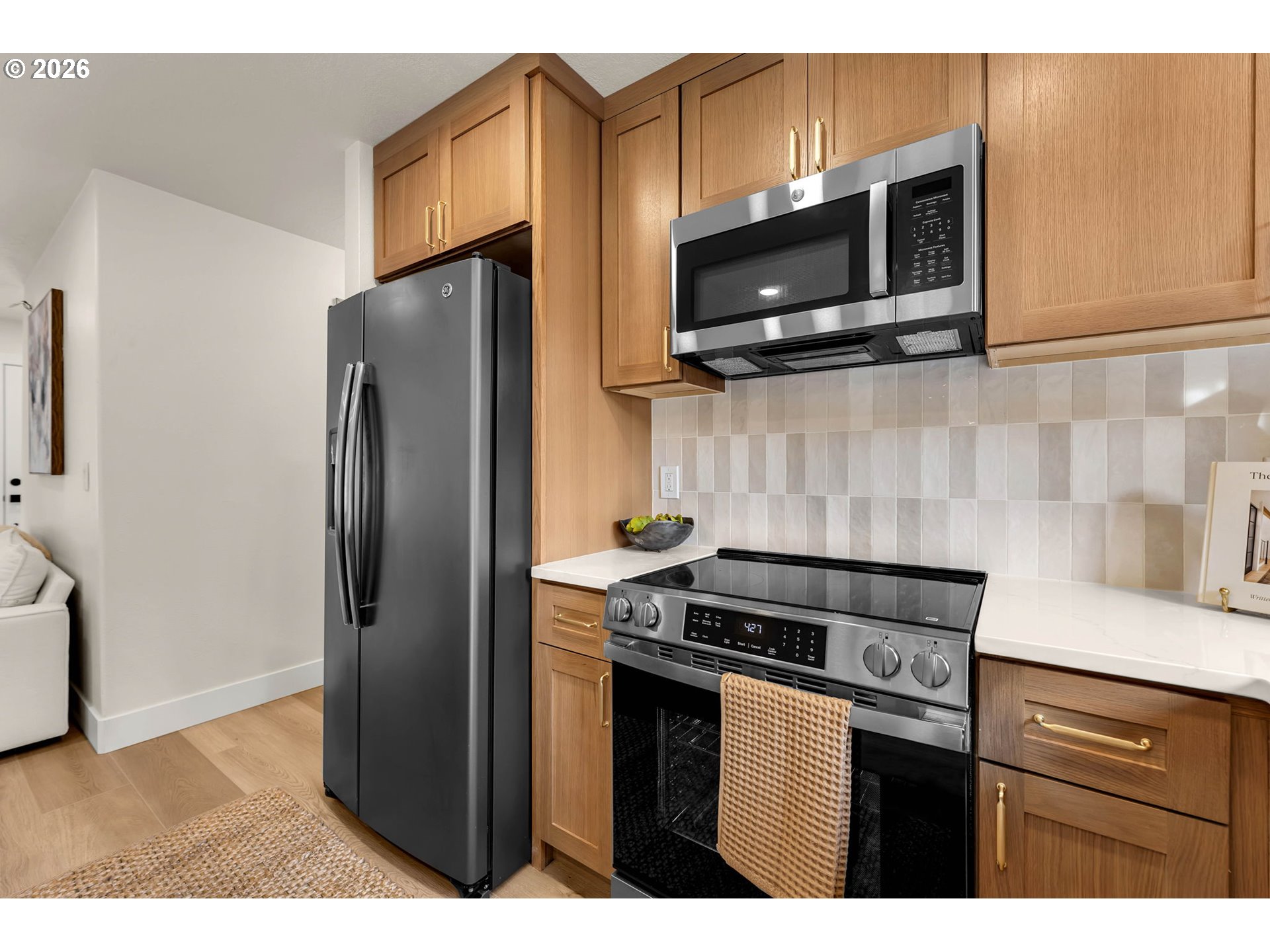 Kitchen with warm wood cabinets, stainless steel appliances, and white tile backsplash.