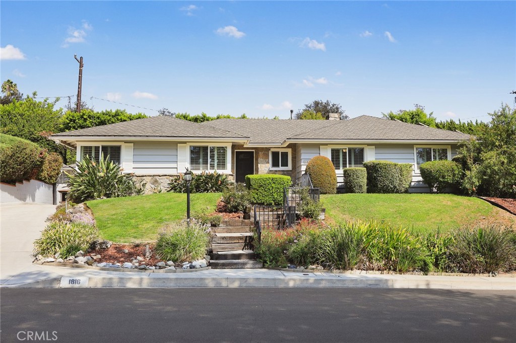 Single-story home with stone accents, landscaped front lawn, and central entry steps.