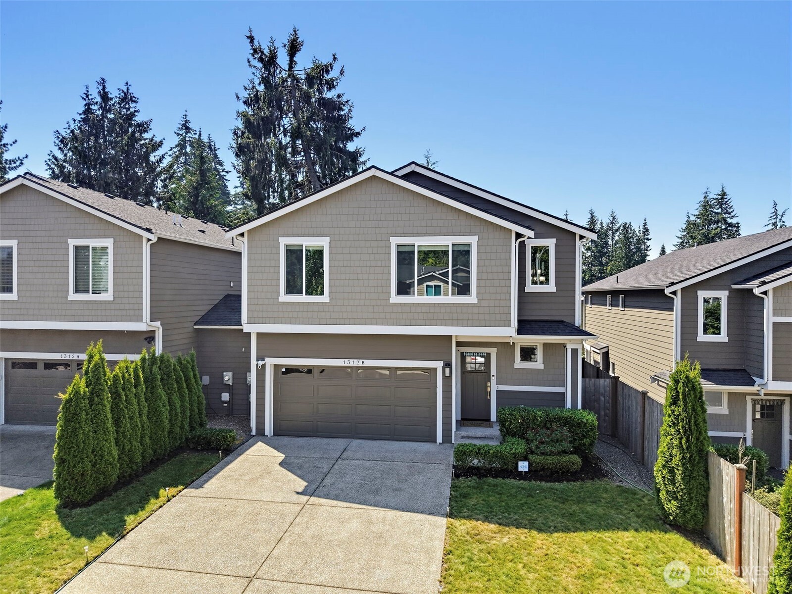 Gray two-story home with white trim, double garage, concrete driveway, and landscaped front yard.
