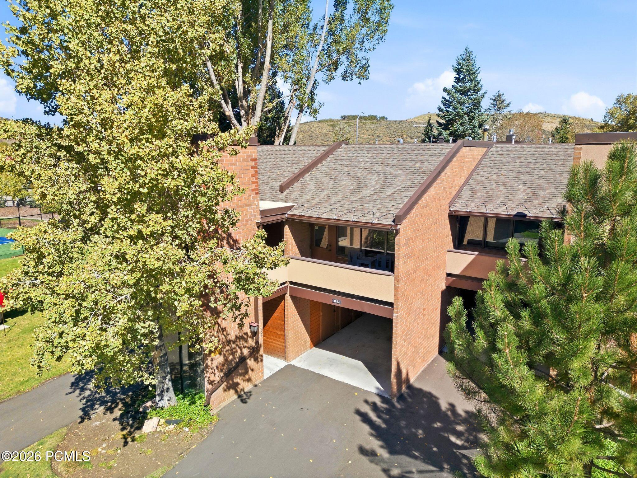 Brick residence with covered entry, framed by mature trees and viewed from above.