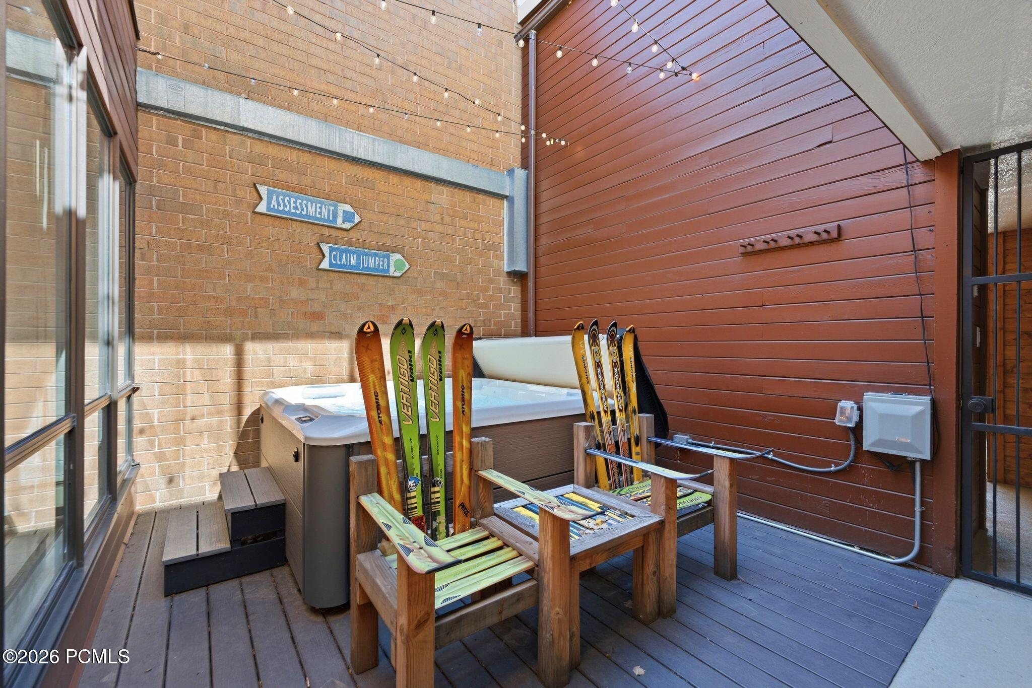 Covered deck with a hot tub and ski racks holding several pairs of skis.