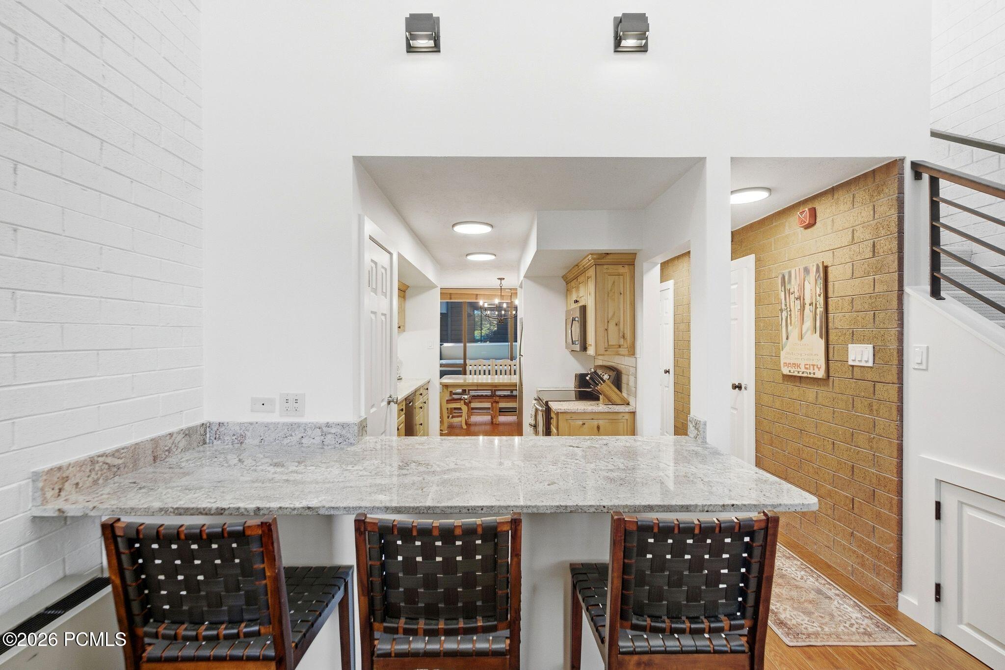 Kitchen with granite breakfast bar, three woven chairs, wood cabinetry, and a dining nook.
