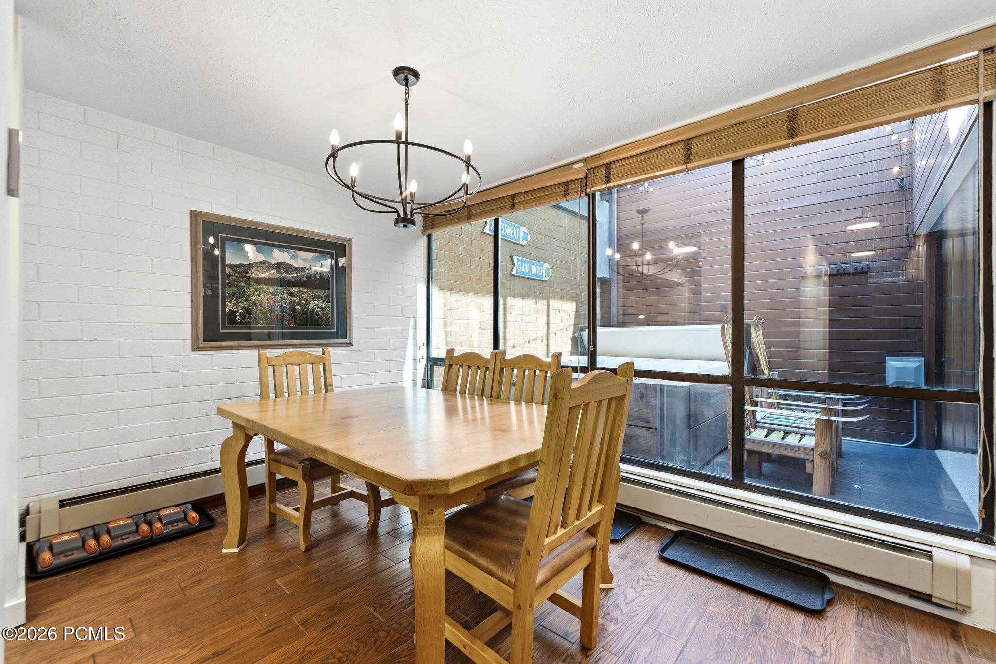 Dining room with a wooden table and chairs beside large windows overlooking a private deck.