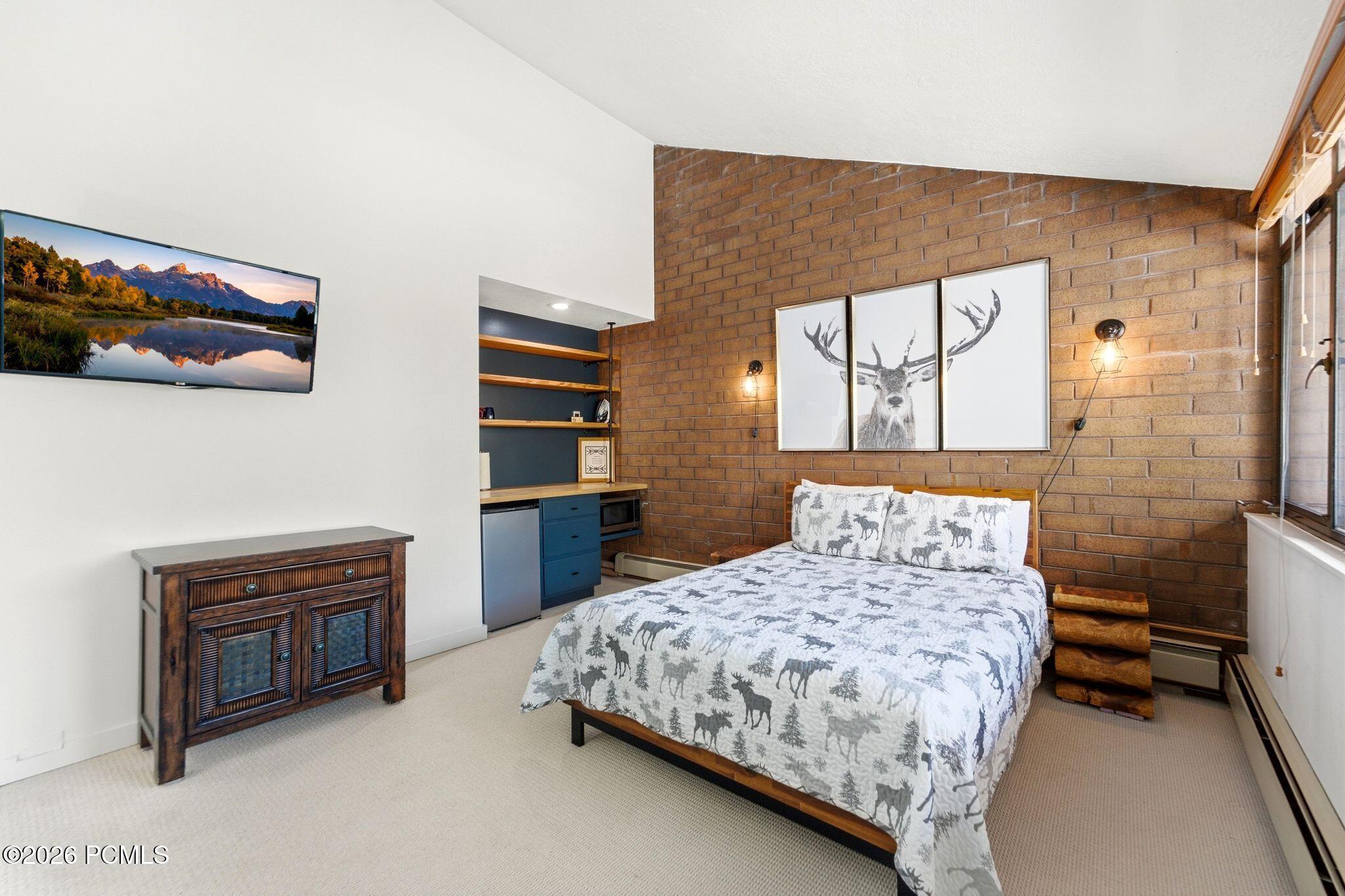 Bedroom with a brick accent wall, deer artwork, and moose-patterned bedding.