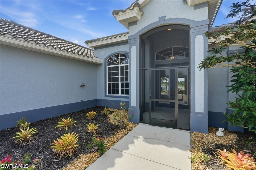 Home entrance with a tall arched glass entry, arched window, and landscaped walkway.