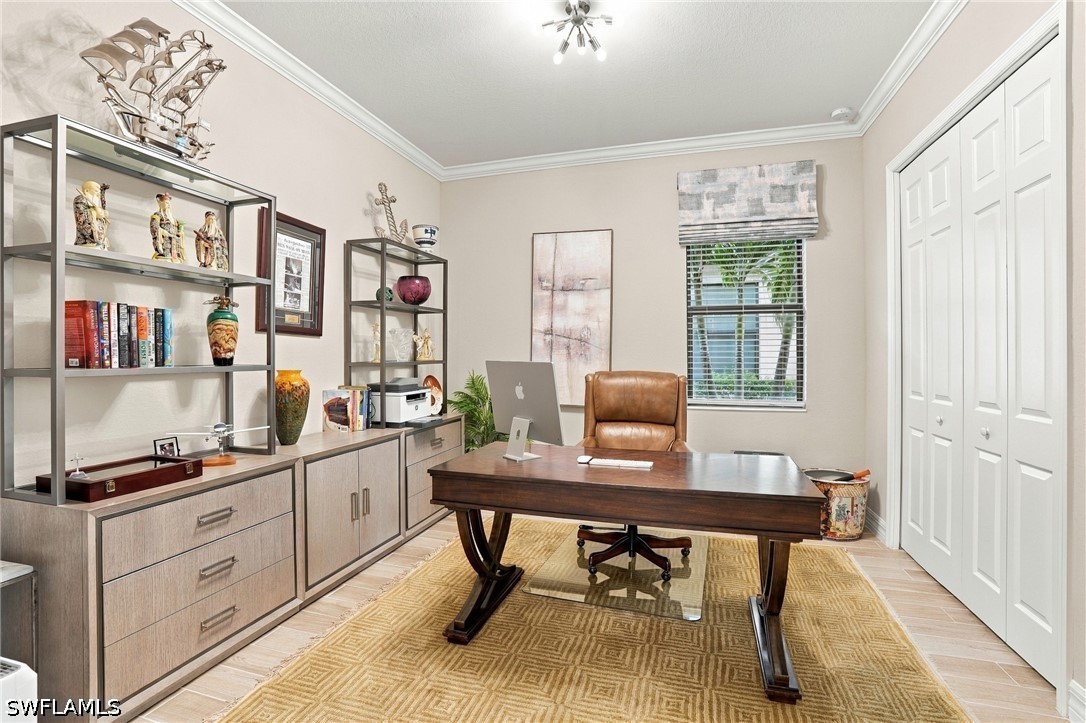 Home office with a dark wood desk, leather chair, built-in shelving, and white closet doors.