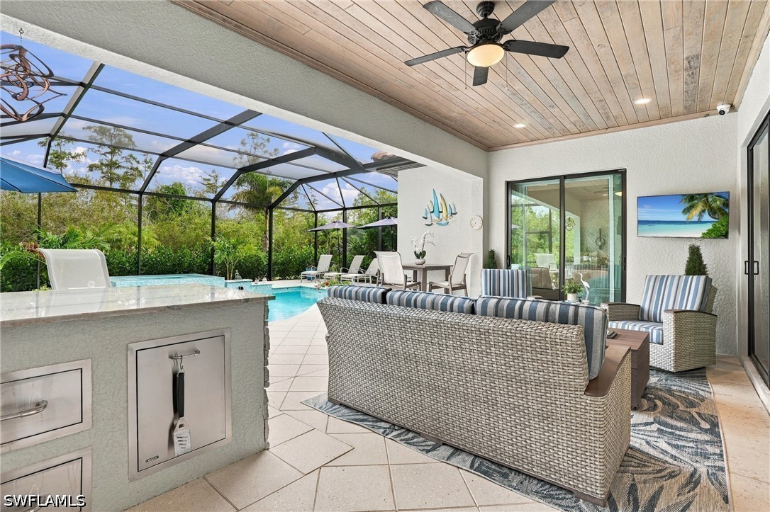 Screened lanai with wicker seating, an outdoor kitchen island, and a pool.