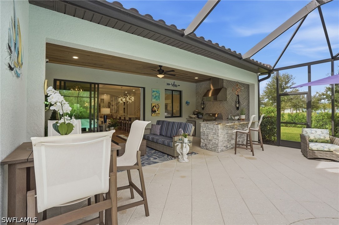 Covered patio with a stone barbecue island, dining table, and lounge seating overlooking the lawn.
