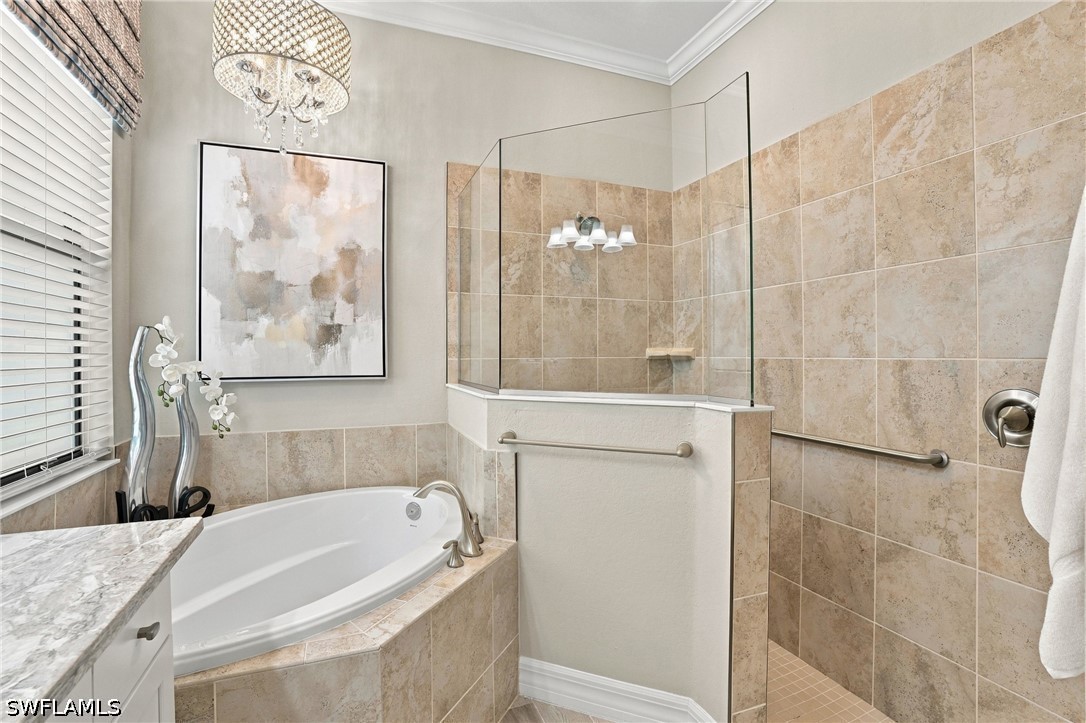 Bathroom with a corner soaking tub and glass-enclosed shower lined with tan tile.