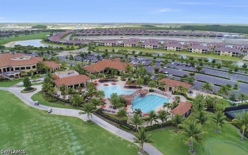 Aerial view of a community clubhouse and resort-style pools surrounded by homes and ponds.