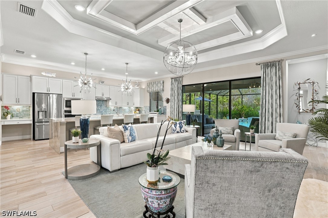 Open-plan living room and kitchen with coffered ceiling and sliding doors overlooking a pool.