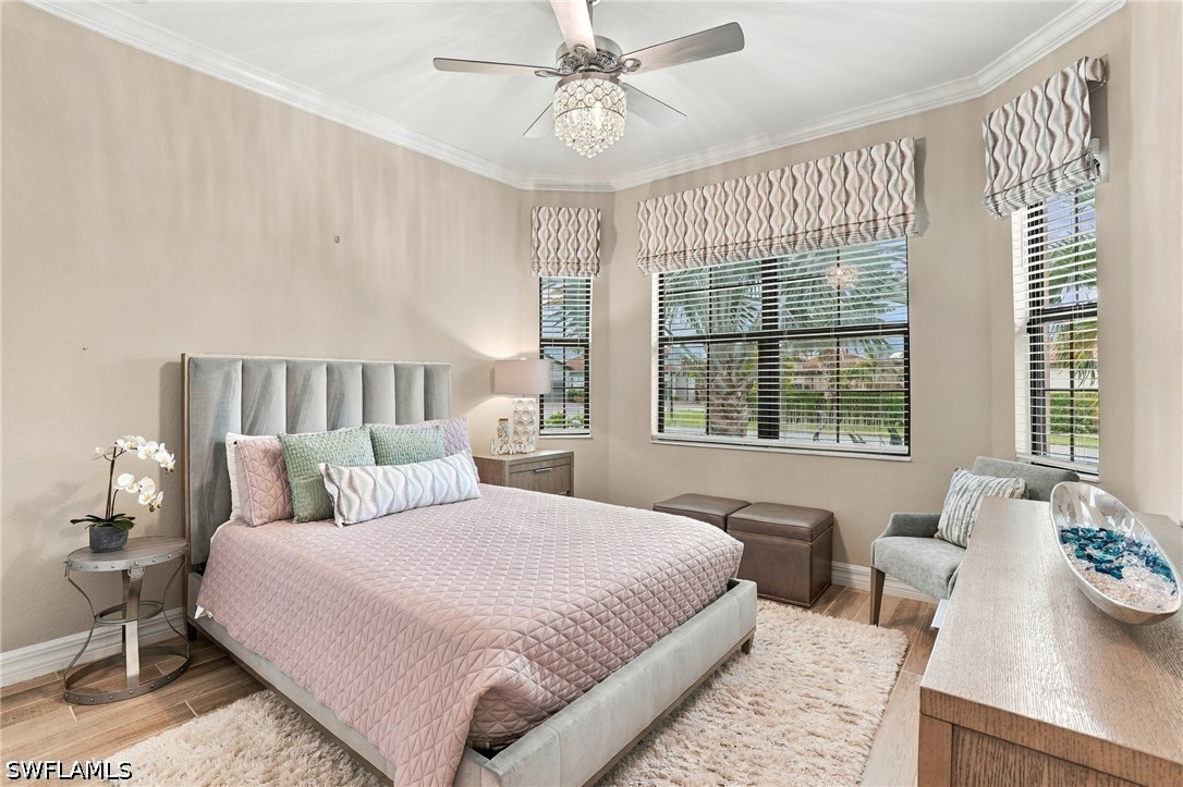 Staged bedroom with a large upholstered bed, patterned shades, and windows overlooking palm trees.