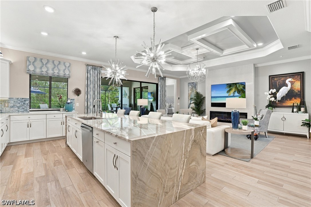 Open-plan kitchen with a large marble island and adjoining living room.