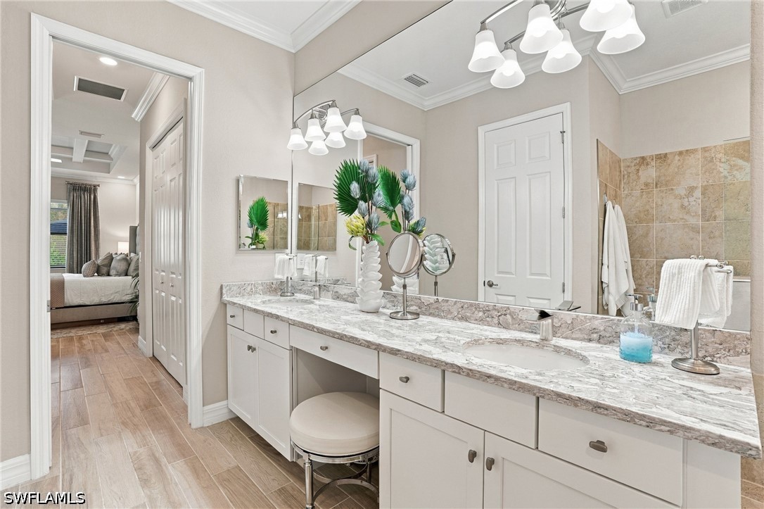 Bathroom with a long double-sink vanity, marble-look countertop, large mirrors, and an adjoining bedroom.