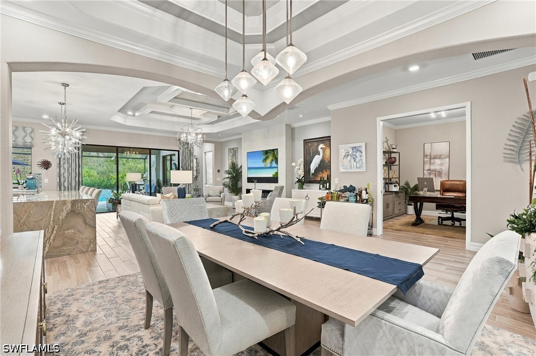 Open-plan dining room with a long table, coffered ceiling, and adjoining living area.